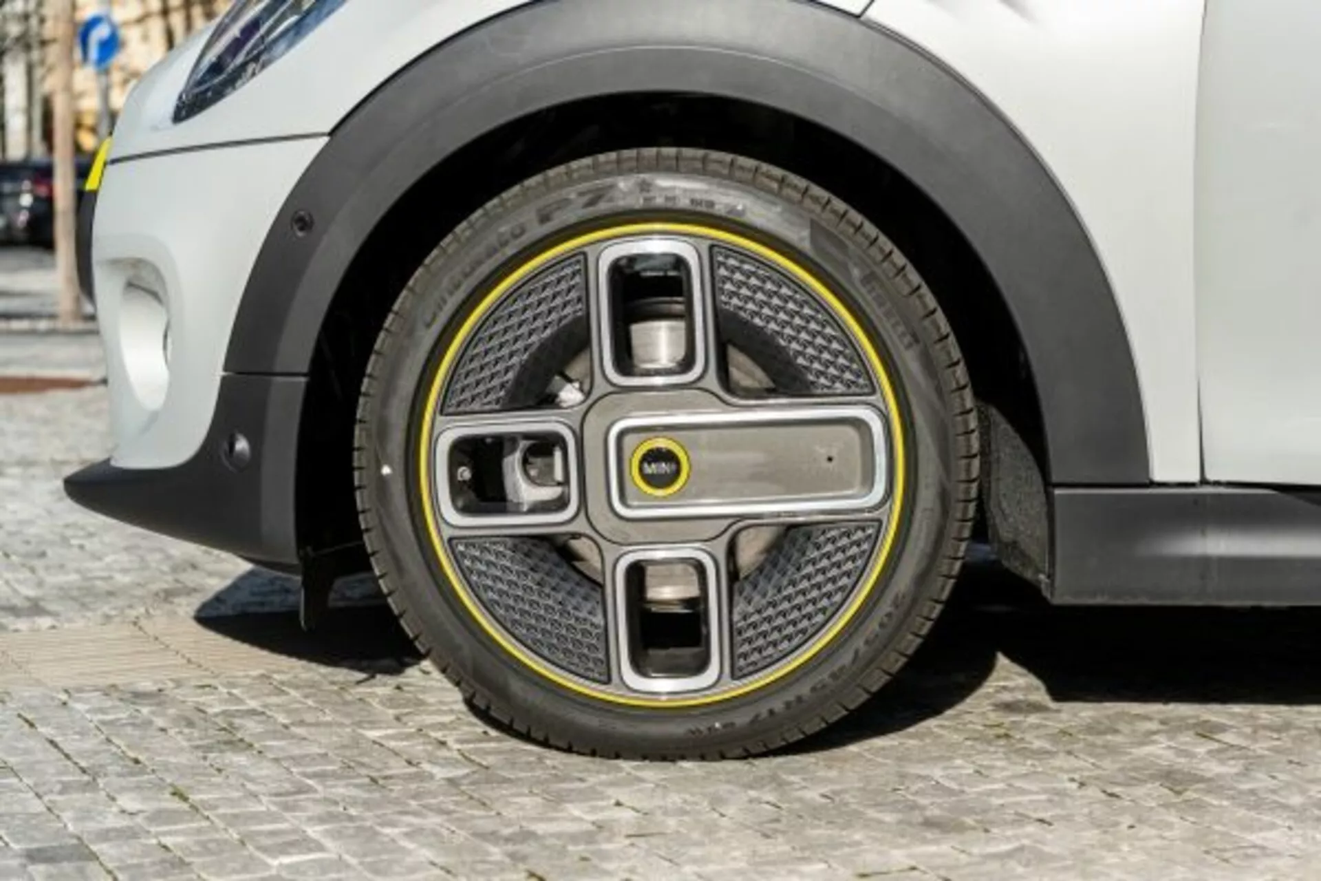 Gros plan sur la roue avant de la Mini Mini 3 portes 2018 avec un design futuriste bicolore et un enjoliveur intégré, évoquant l'innovation des véhicules électriques et une aérodynamique avancée, sur fond de carrosserie blanche