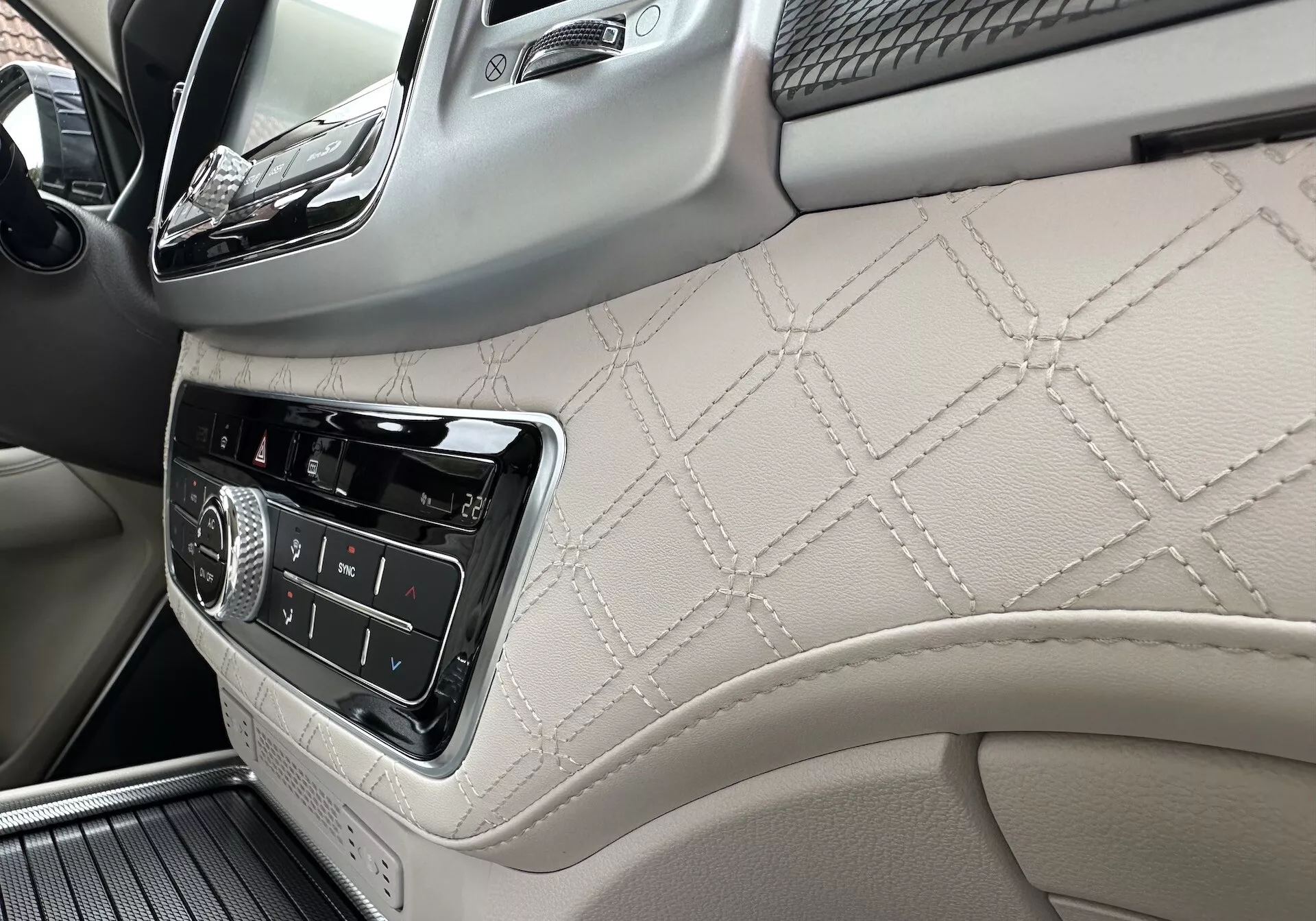 Intérieur du SsangYong Rexton 2021 axé sur le tableau de bord côté passager et partie du panneau de porte avant avec cuir cousu en diamant, commandes d'infodivertissement et détails en bois de luxe