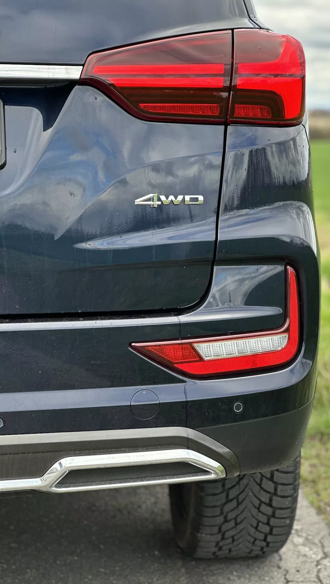 Vue détaillée du coin arrière du SsangYong Rexton 2021 montrant le bloc lumineux arrière LED, badge 4WD, capteur de stationnement, couverture d'échappement intégrée en peinture métallique