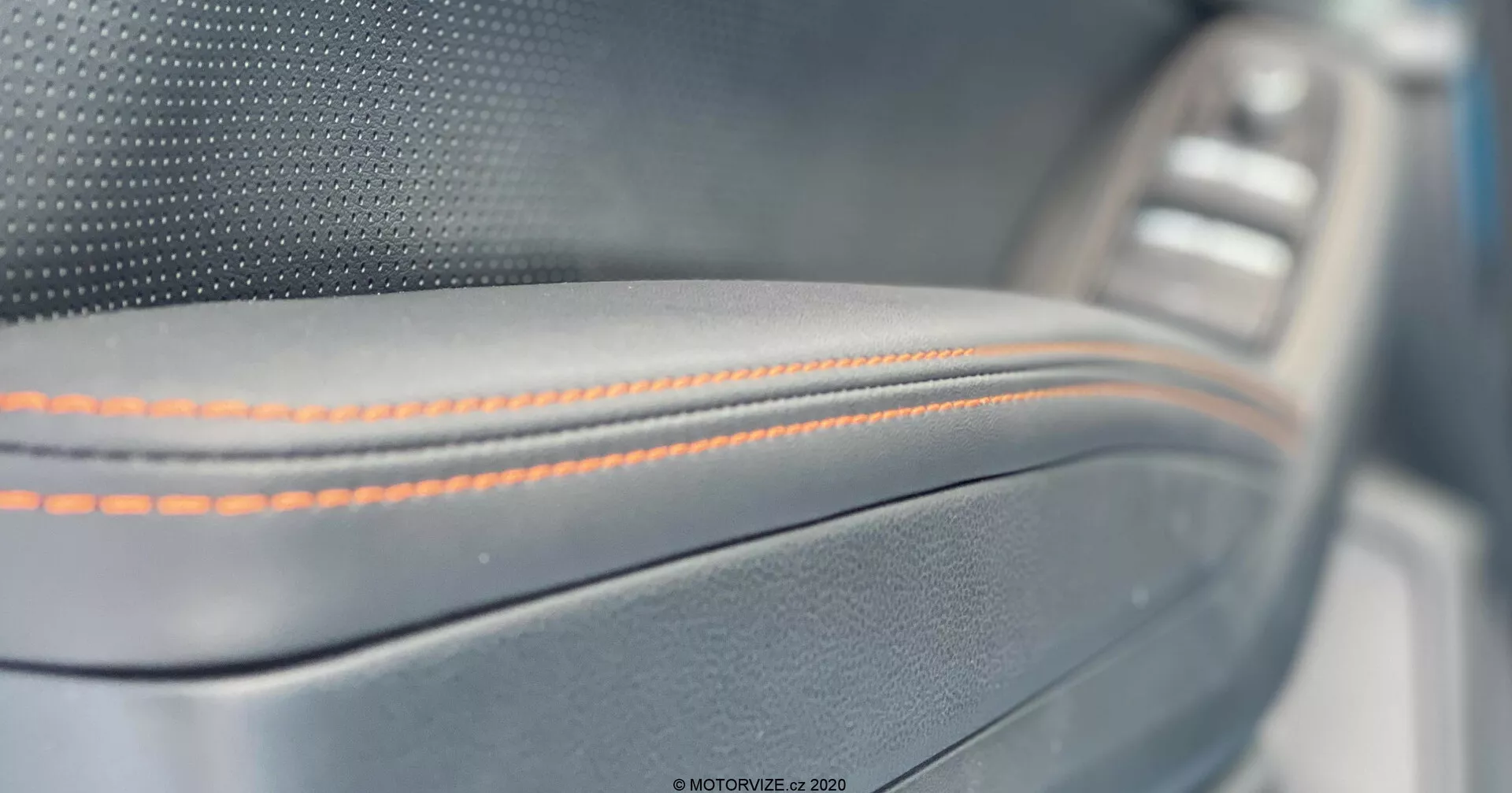 Gros plan sur le panneau de porte intérieur de la Subaru XV 2018, avec des coutures orange précises sur un matériau semblable au cuir avec une garniture métallique et un panneau de commande de fenêtre légèrement flou en arrière-plan, mettant en avant un artisanat premium et des détails de luxe.