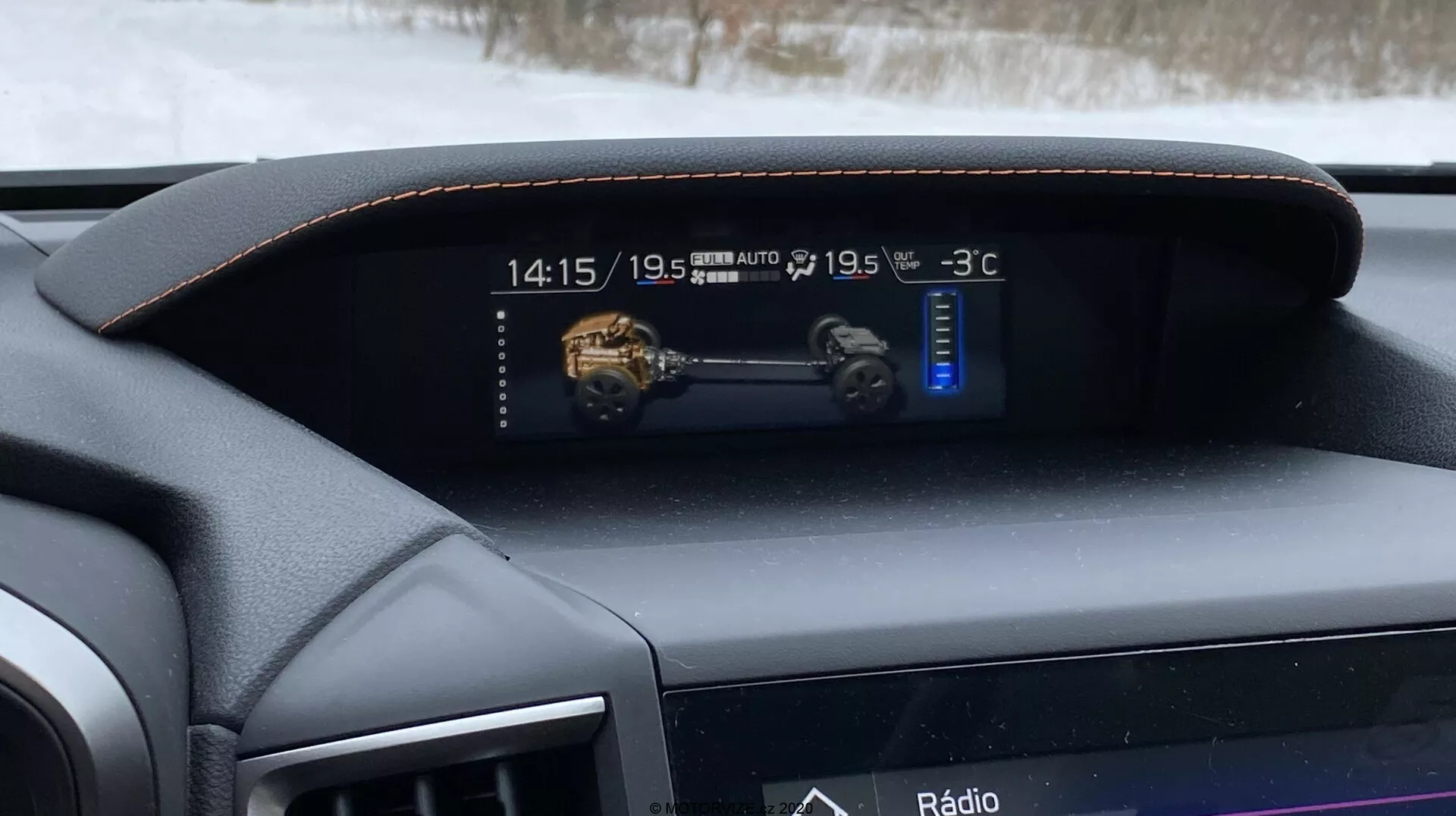 Vue intérieure de la Subaru XV 1.6i Trend Lineartronic 2018 se concentrant sur le tableau de bord numérique depuis le siège du conducteur. Le tableau de bord encadré de cuir avec des coutures décoratives renforce l'apparence haut de gamme. L'affichage numérique montre l'heure (14:15), un modèle 3D du véhicule, des commandes de climatisation bi-zone réglées sur 'LO' et une température extérieure de -3°C. En dessous, un écran plus étroit affiche l'option de divertissement active 'Radio', indiquant un système d'infodivertissement intégré.
