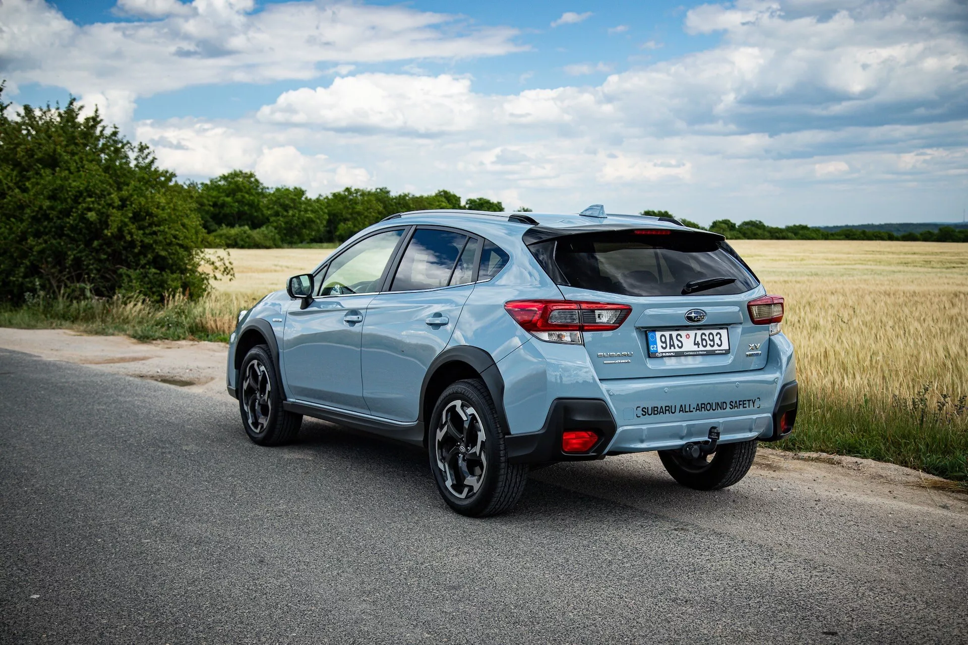 SUV compact Subaru XV bleu clair 2021 photographié sous un angle arrière de trois quarts mettant en évidence le côté droit, posture dynamique sur route pavée avec vue claire sur l'aileron arrière, les roues en alliage, les feux arrière LED, l'insigne du modèle, la pointe d'échappement unique et les caractéristiques technologiques potentielles