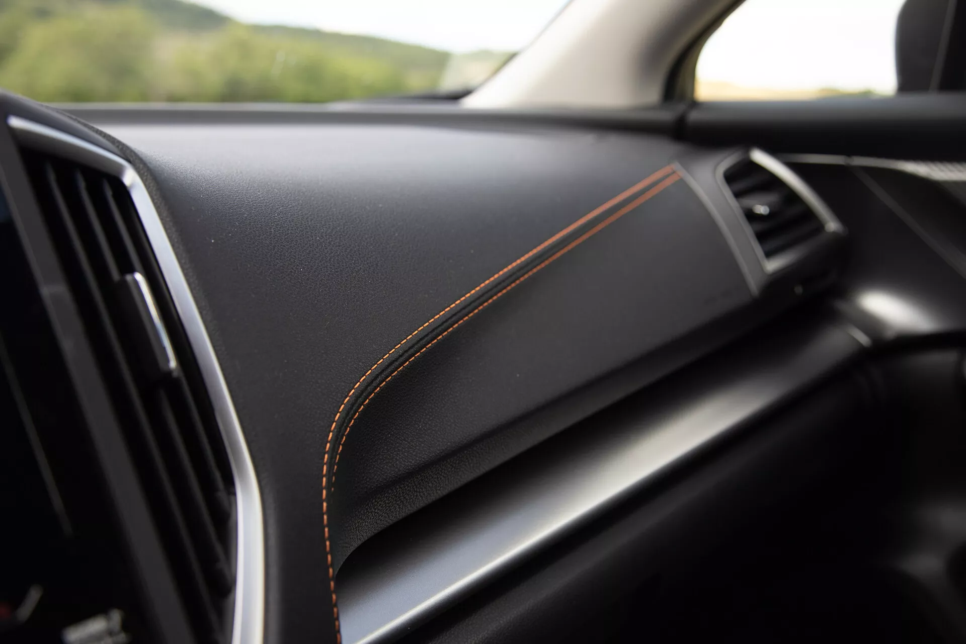 Détail intérieur du Subaru XV 2021 montrant un tableau de bord en matériau noir haut de gamme avec des coutures orange contrastantes, suggérant une finition de luxe et une qualité de construction élevée