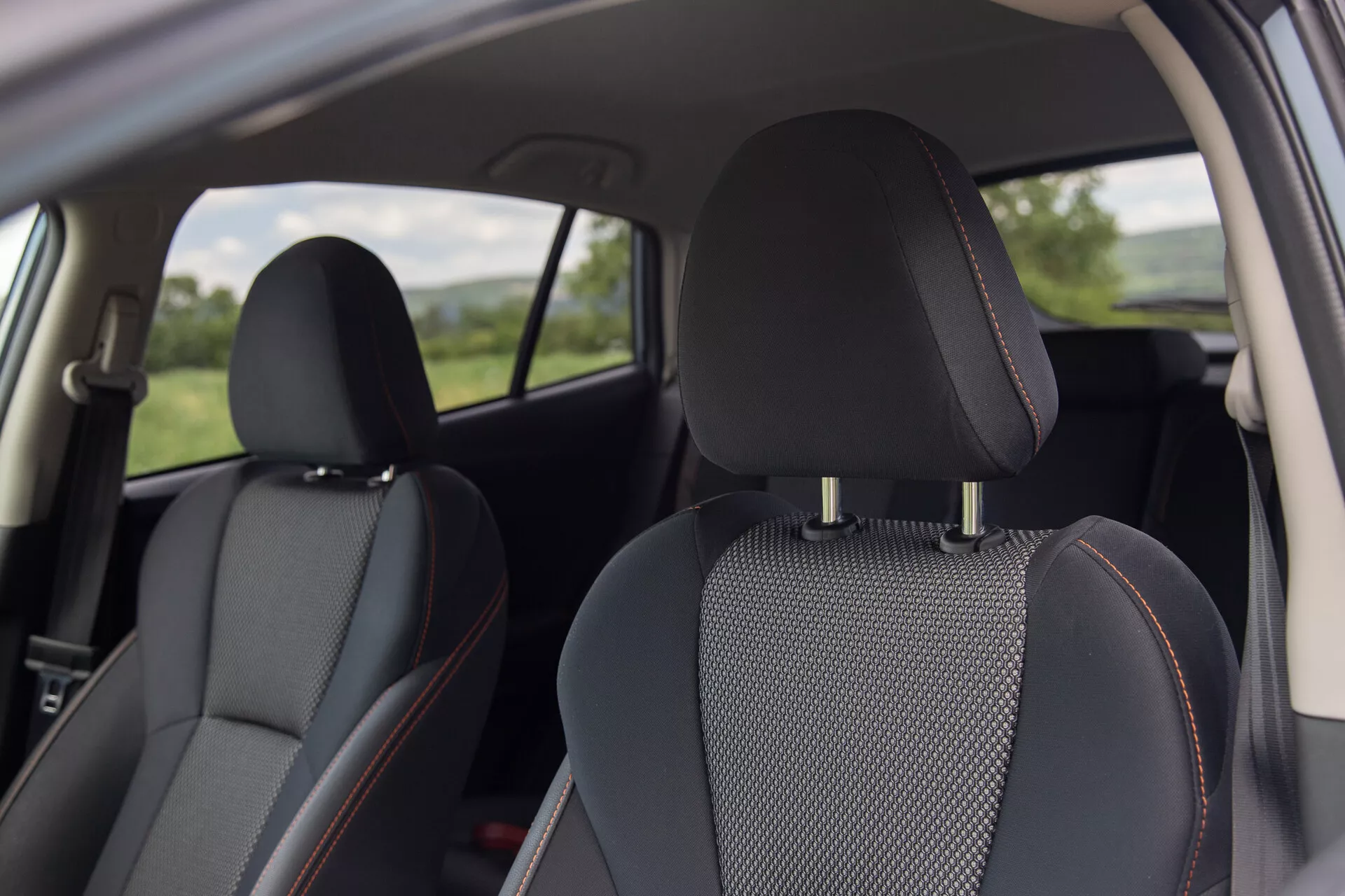Vue intérieure du Subaru XV 2021 présentant des sièges en cuir noir avec des inserts en tissu à motifs et des coutures oranges distinctives, axée sur le confort et le design du point de vue d'un passager arrière