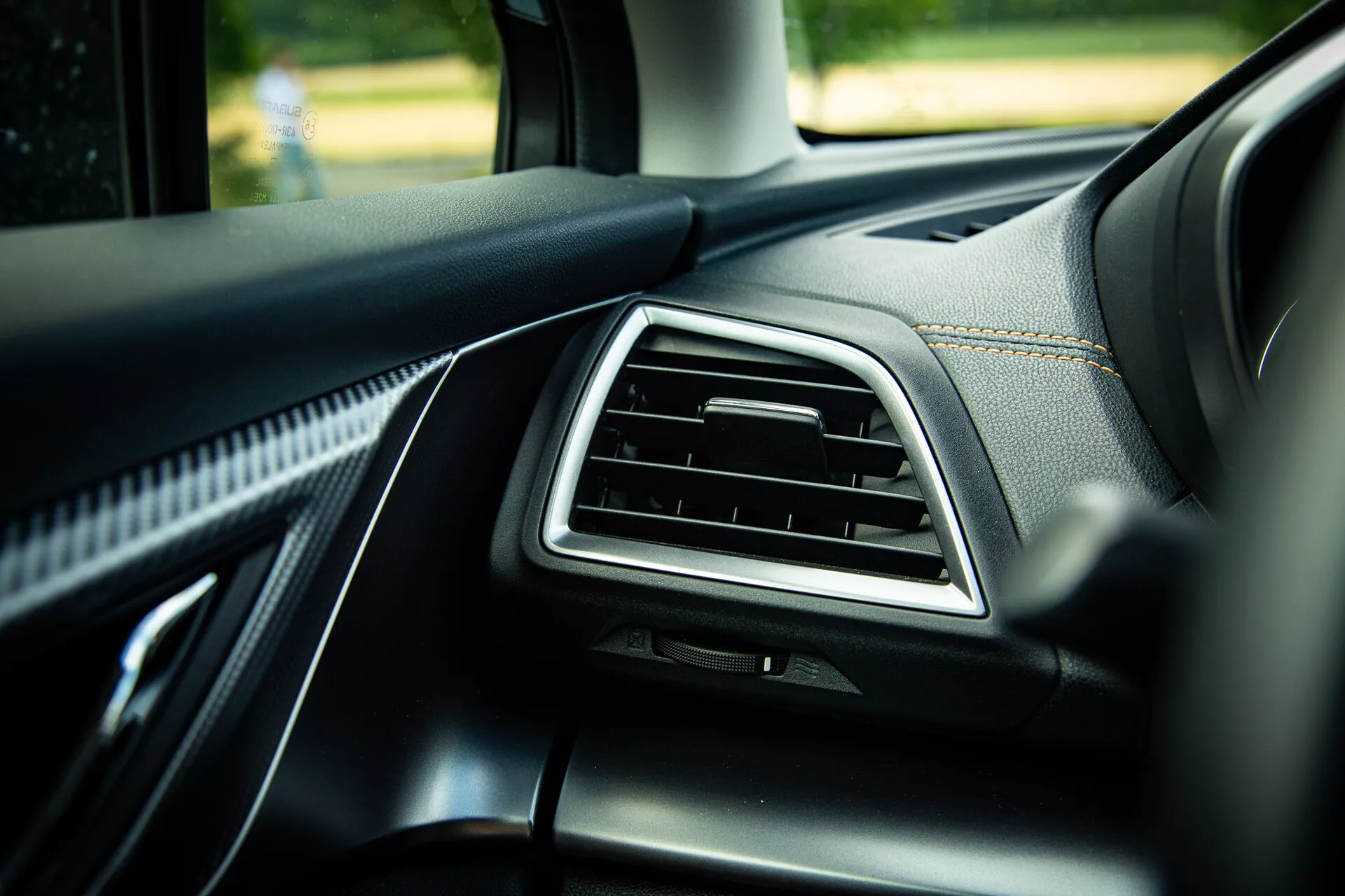 Détail intérieur du Subaru XV 2021 montrant le tableau de bord côté passager avec aération accentuée en chrome, garniture en cuir noir de qualité avec coutures visibles et matériaux soft-touch, photographié sous un angle de 45 degrés mettant en évidence des éléments de design moderne à la lumière naturelle du jour