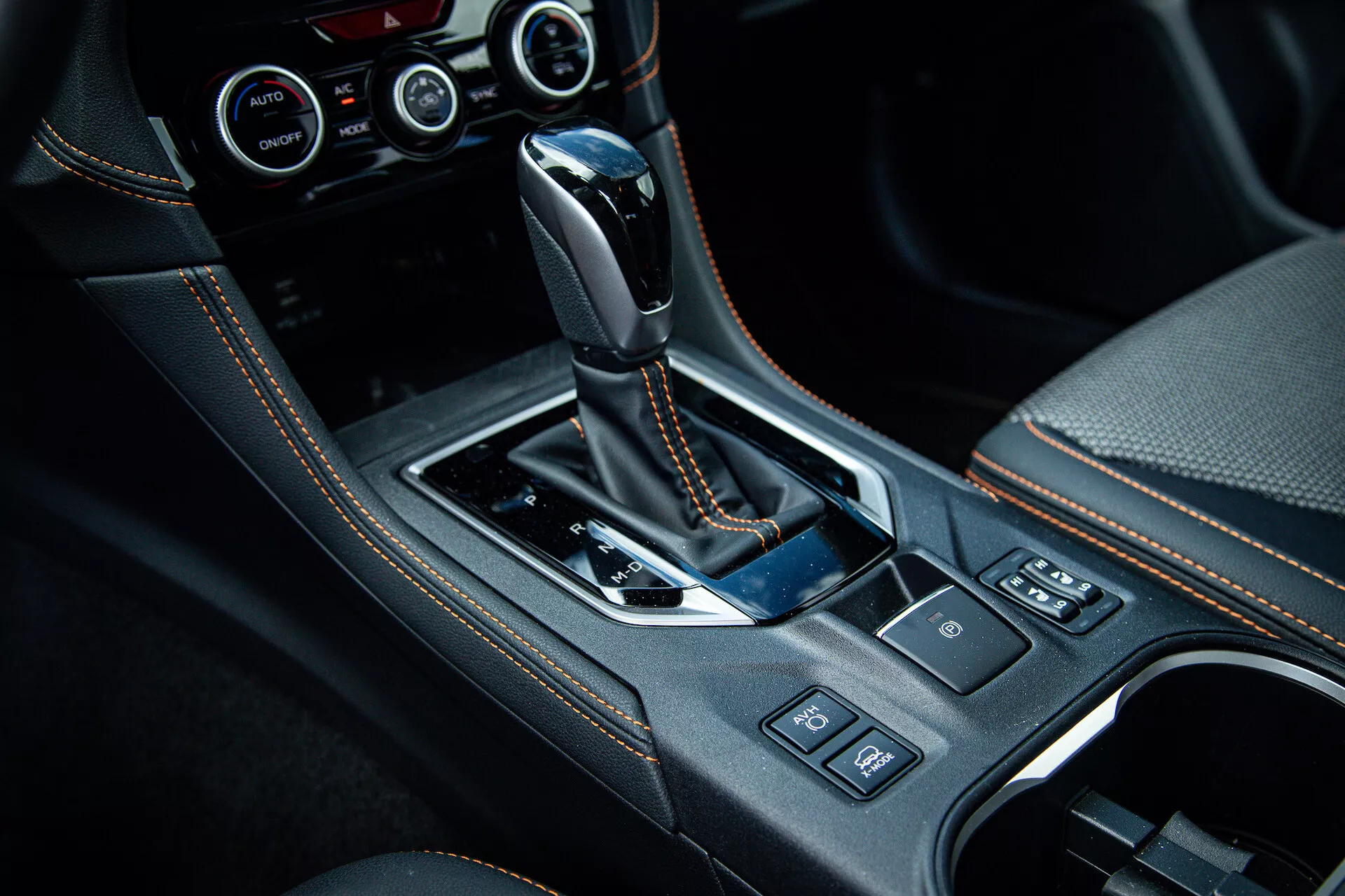 Console centrale du Subaru XV 2021 avec levier de vitesse automatique enveloppé de cuir, finitions en noir brillant, détails chromés, porte-gobelets, boutons de contrôle et système de contrôle climatique avancé visible sur photo d'intérieur de haute qualité