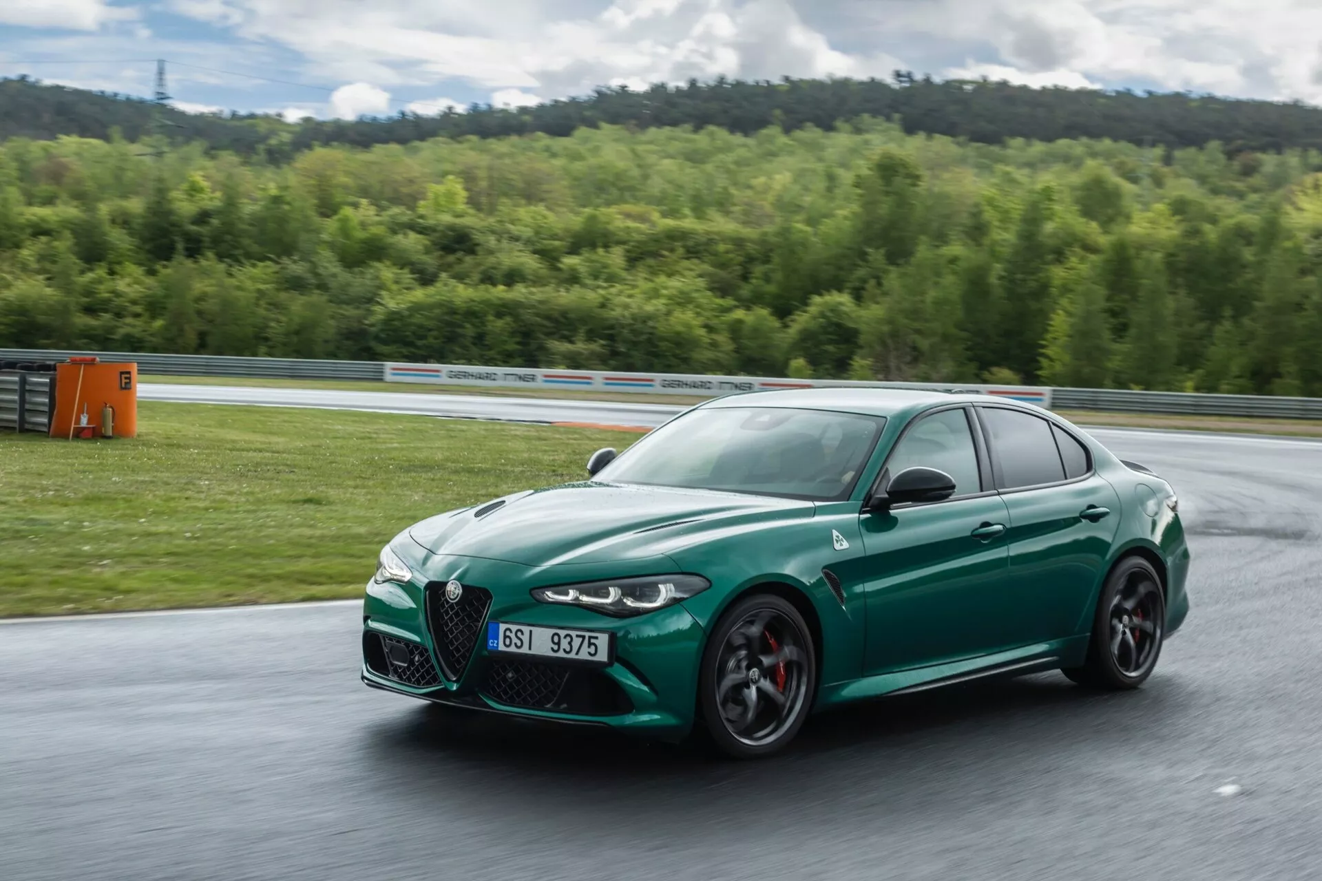 Alfa Romeo Giulia Quadrifoglio 2023 en mouvement, vue avant trois quarts présentant un design aérodynamique, de grandes entrées d'air et des caractéristiques de performance sportive sur un circuit de course.