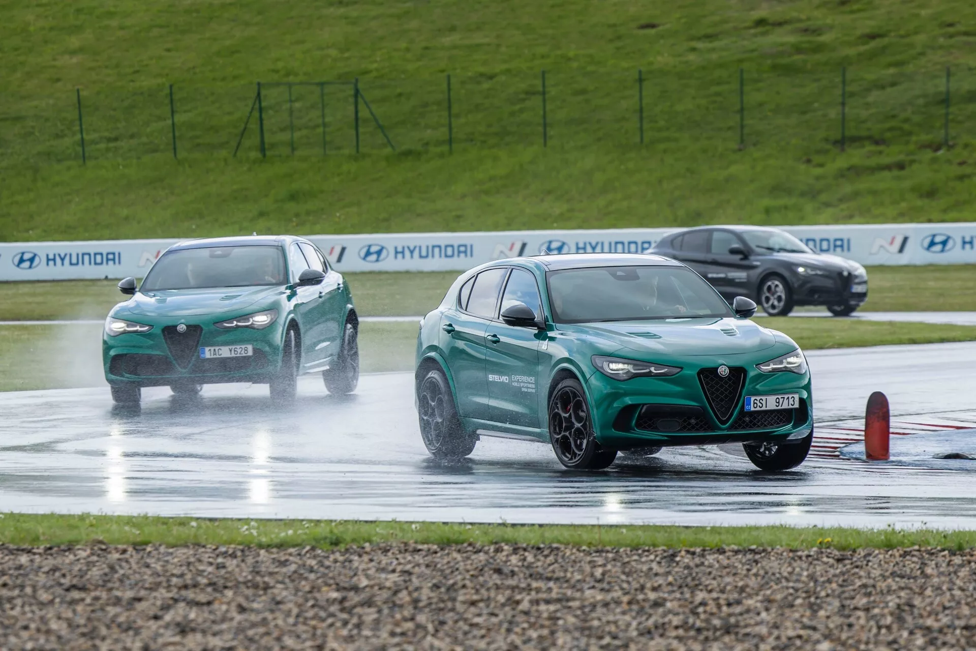 Alfa Romeo Giulia Quadrifoglio 2023 participant à un test de maniabilité sur route mouillée, affichant un design sportif avec grille frontale visible, feux de jour LED et caractéristiques orientées performance sur un fond d'éclaboussures d'eau induites par le mouvement