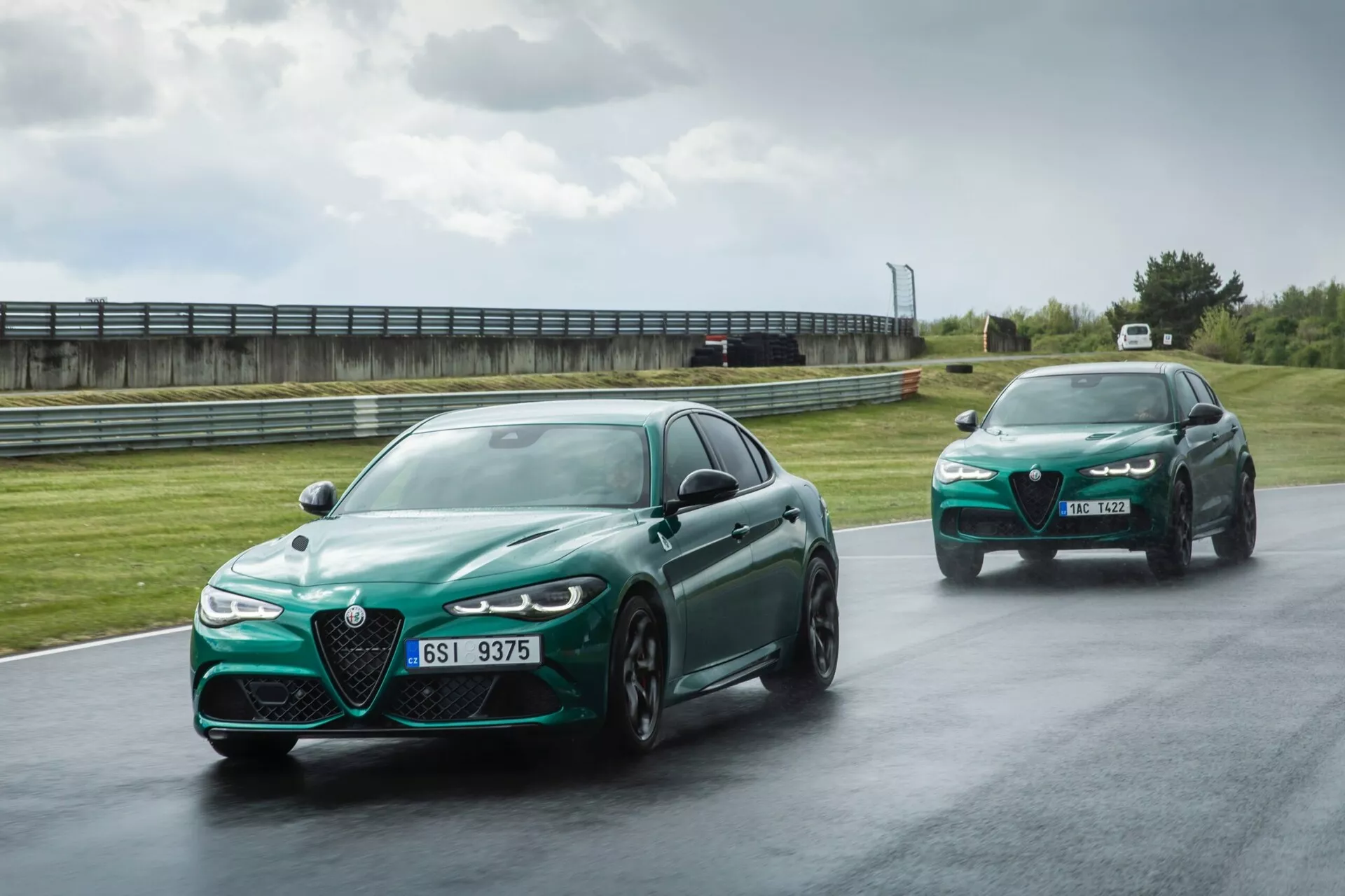 Alfa Romeo Giulia Quadrifoglio 2023 en vert métallisé, présentant sa grande grille distinctive, ses phares LED et ses jantes en alliage sportives sur une piste mouillée, mettant en lumière des caractéristiques de performance et de sécurité avancées