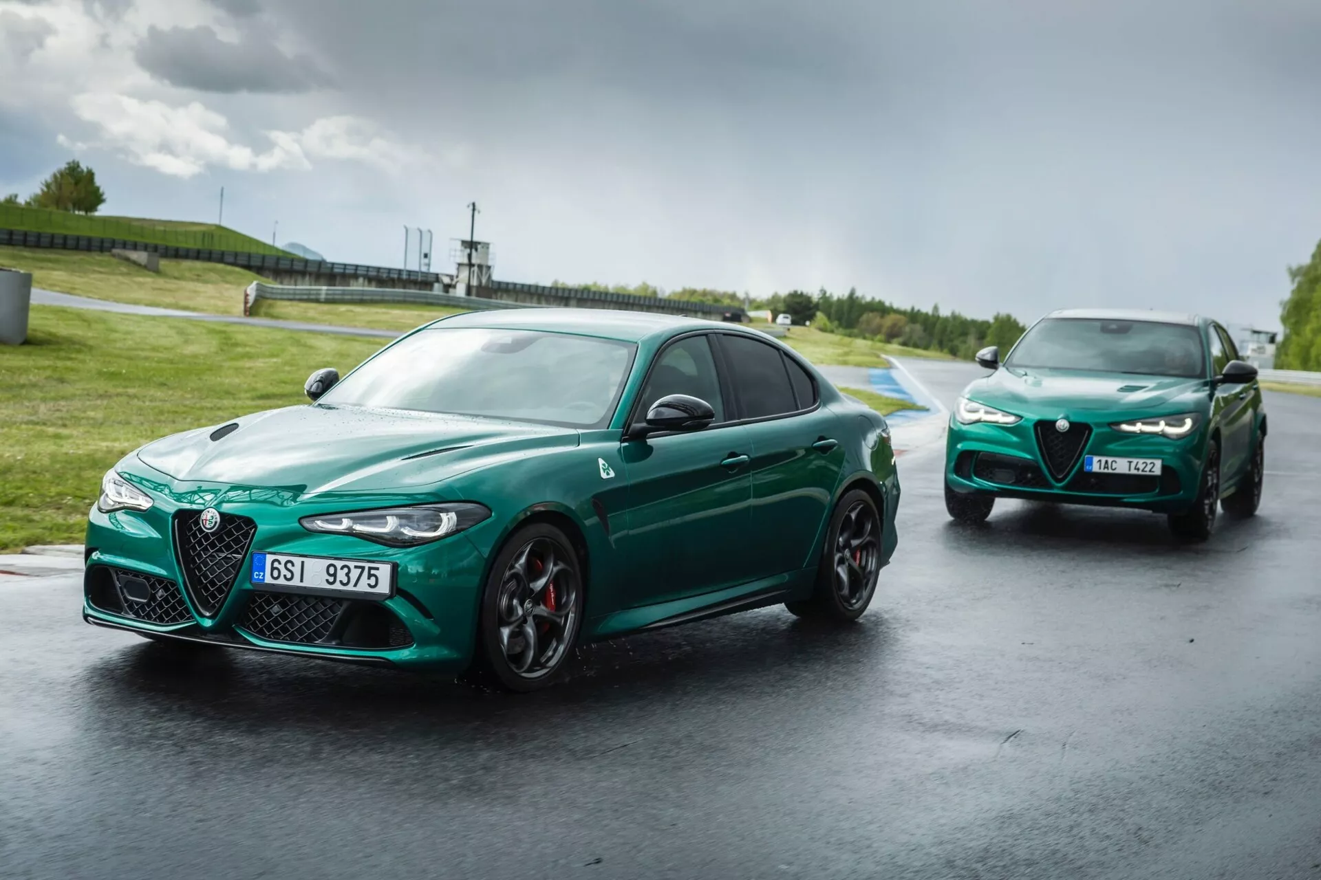 Alfa Romeo Giulia Quadrifoglio 2023 sur circuit mouillé, montrant un design avant agressif avec une grille Scudetto et des phares LED élancés, en vert vibrant