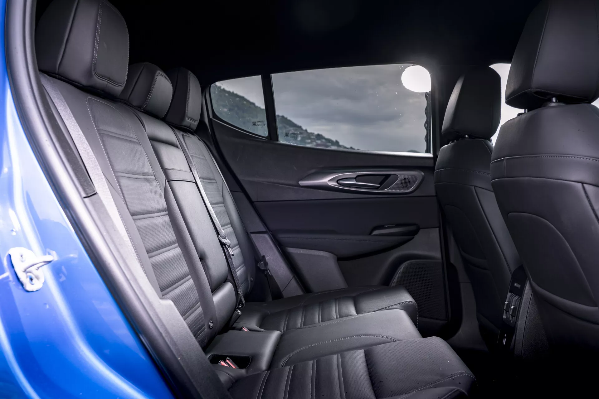 Intérieur de l'Alfa-Romeo Tonale 2022 montrant des sièges arrière en cuir de luxe avec coutures détaillées et design ergonomique, porte incluse, mettant en évidence des caractéristiques haut de gamme