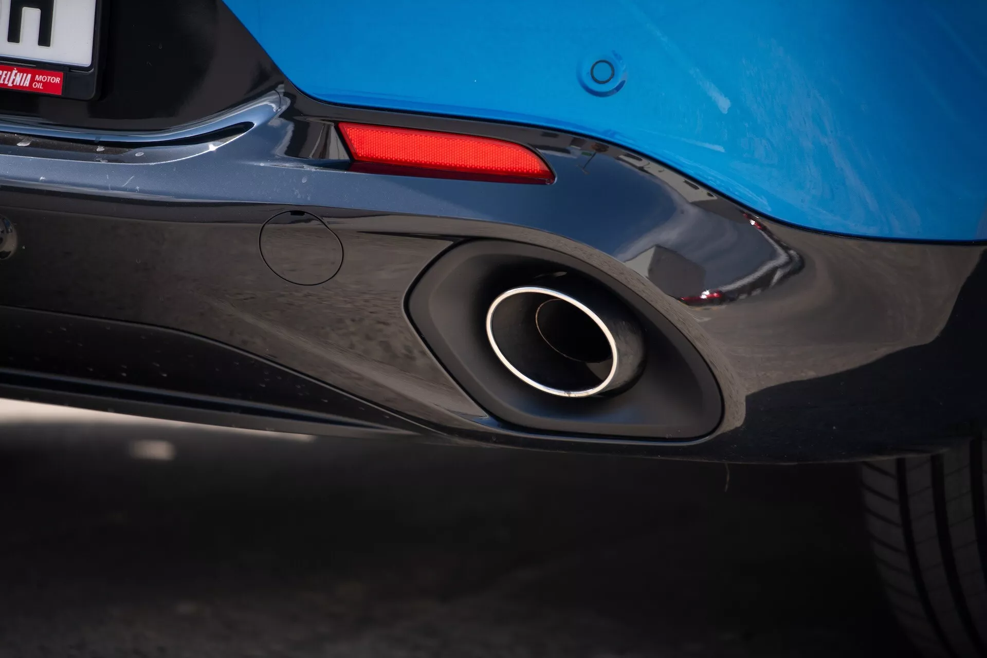 Gros plan sur la partie arrière de l'Alfa Romeo Tonale 2022 mettant en avant la sortie d'échappement sportive, le design aérodynamique du pare-chocs arrière et la couleur bleue de la carrosserie avec un aperçu du feu arrière