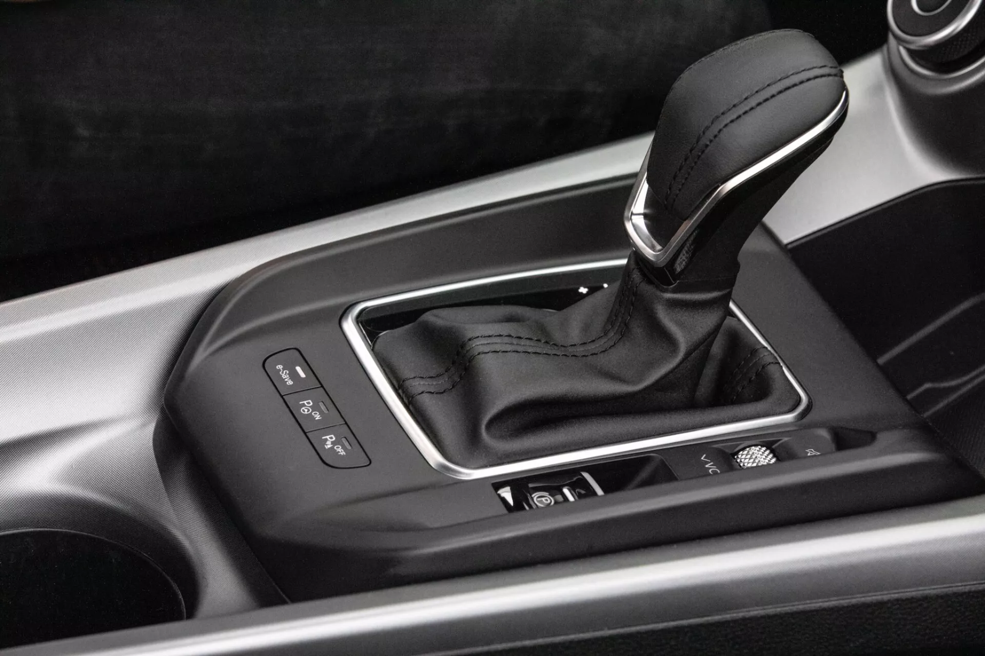 Vue intérieure détaillée de la console centrale de l'Alfa-Romeo Tonale 2022 avec levier de vitesse automatique dans un boîtier argenté avec indicateurs de sélection de vitesse, boutons de contrôle intégrés et finition de haute qualité
