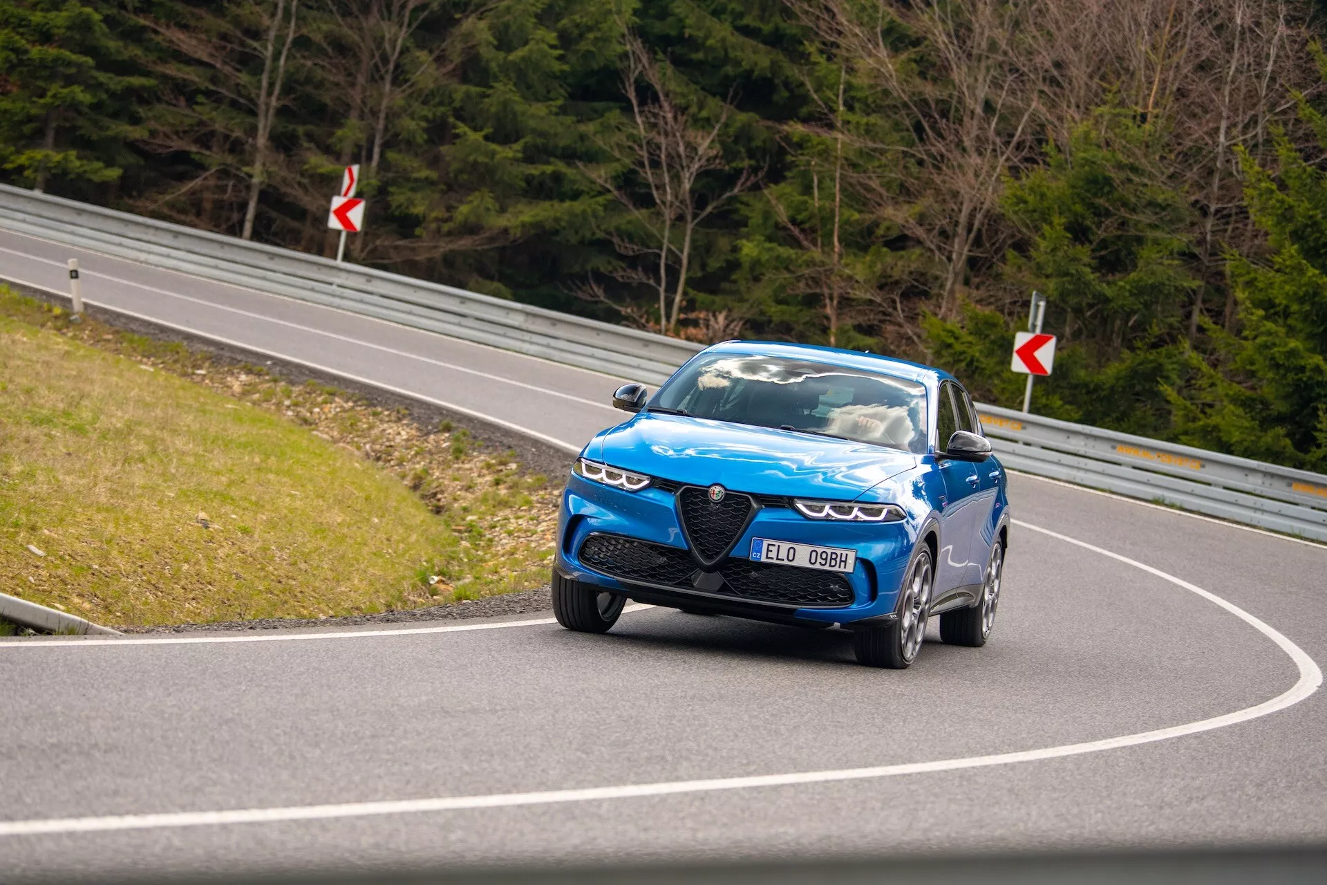 Conduite dynamique de l'Alfa Romeo Tonale 2022 sur route sinueuse présentant vue avant, phares LED, grille distinctive et roues hautes performances