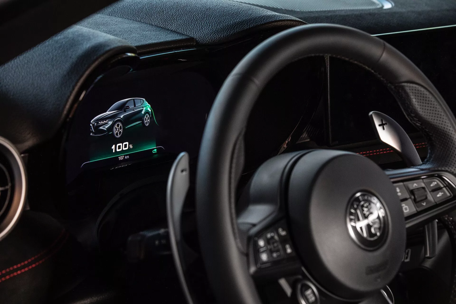 Intérieur de l'Alfa Romeo Tonale 2022 montrant la perspective du conducteur avec tableau de bord numérique, volant multifonction et indicateurs de véhicule électrique