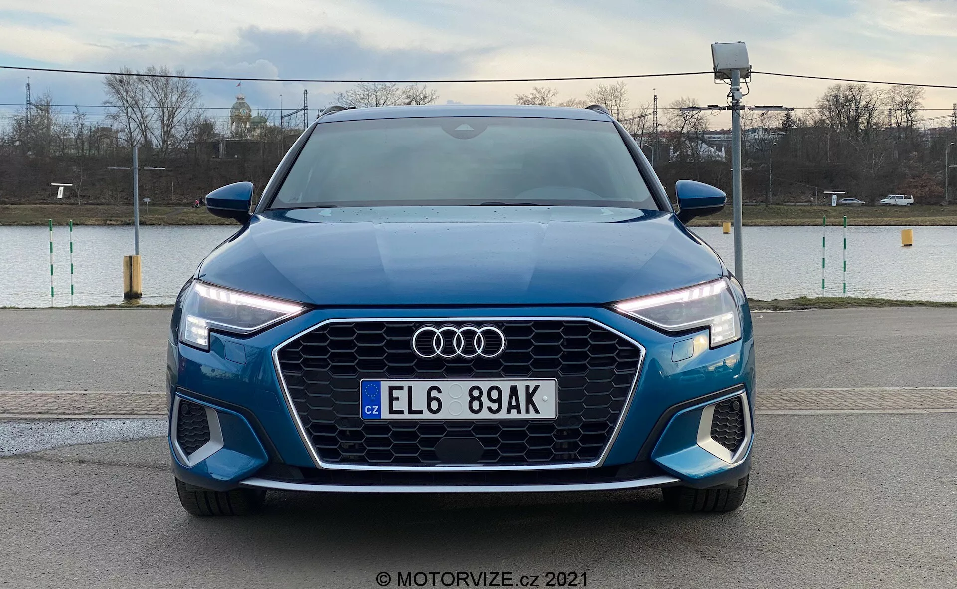 Vue avant de l'Audi A3 Sportback 2020 bleue présentant sa calandre Singleframe proéminente avec un design hexagonal, le logo Audi au centre, des phares LED avec des feux diurnes et un pare-chocs avant avec des prises d'air supplémentaires et des phares antibrouillards possibles, sur un fond extérieur.