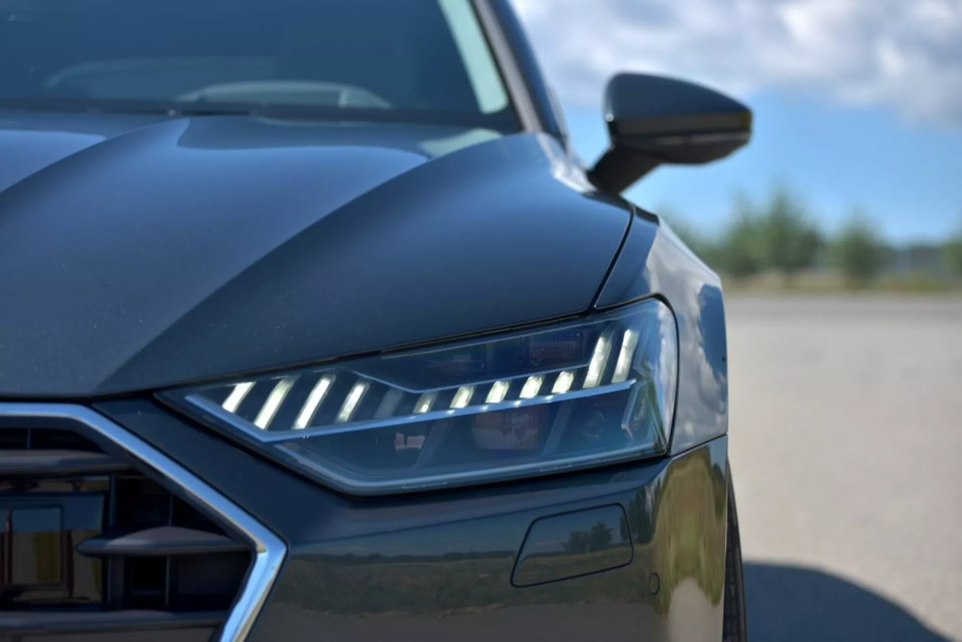 Gros plan de l'Audi A7 Sportback 2018 mettant en lumière la conception des phares LED, vue partielle de la grille et lignes aérodynamiques depuis un angle bas, présentant les caractéristiques d'une voiture de luxe moderne et de la technologie d'éclairage avancée