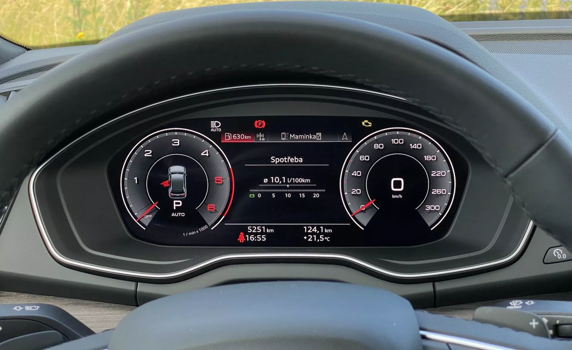 Vue intérieure d'une voiture Audi Q5 Sportback 2020 se concentrant sur le tableau de bord derrière le volant depuis la perspective du siège du conducteur, présentant un tableau de bord mixte analogique et numérique avec deux jauges circulaires principales (compteur de tours et compteur de vitesse) et un affichage central numérique montrant des informations sur le véhicule telles que la consommation de carburant, la distance parcourue, la température extérieure et l'heure.