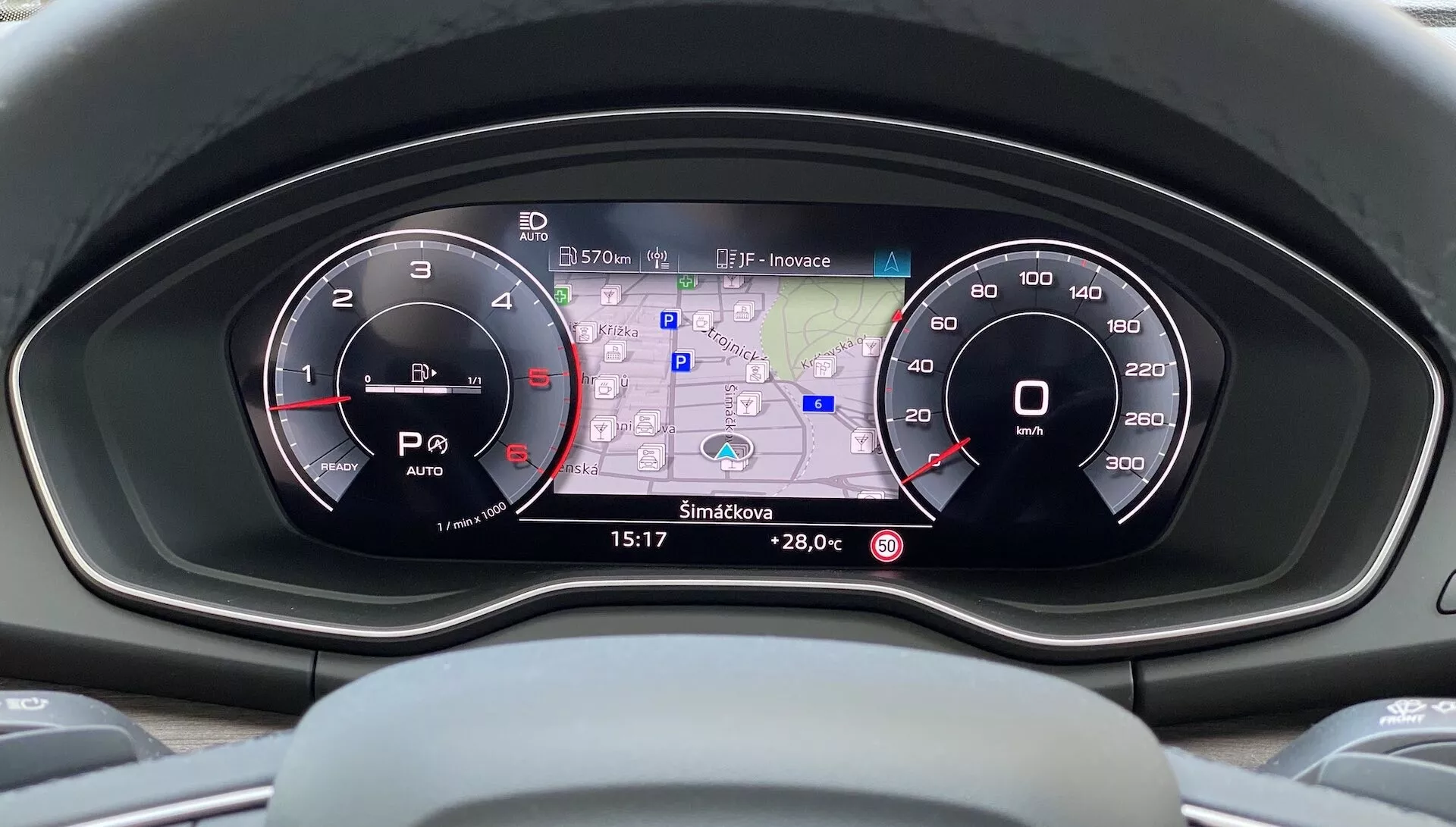 Vue du conducteur sur le tableau de bord moderne de l'Audi Q5 Sportback 2020 mettant en avant le tableau de bord avec deux cadrans analogiques et un affichage numérique central affichant une carte GPS, la lecture de la température, la consommation de carburant, les indicateurs de mode de conduite et l'heure dans une interface haute résolution en couleur.