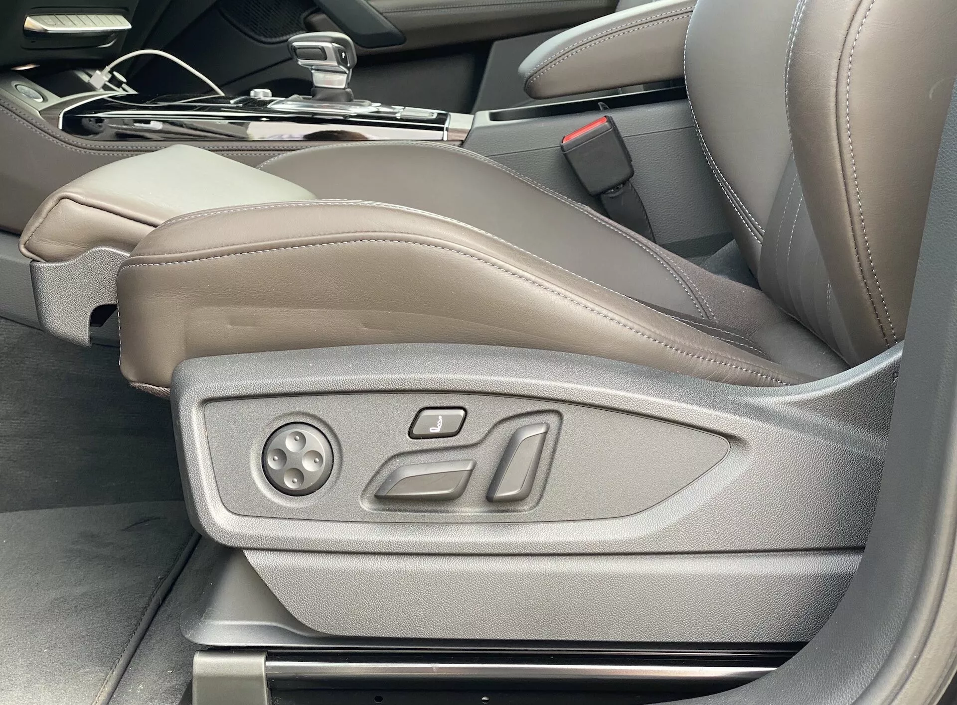 Vue intérieure de l'Audi Q5 2020 Sportback montrant le siège côté conducteur en cuir beige/marron clair avec commandes de réglage électronique, soulignant le luxe et la technologie de siège avancée, y compris les réglages de mémoire potentiels; image prise sous un certain angle depuis l'extérieur de la porte conducteur.