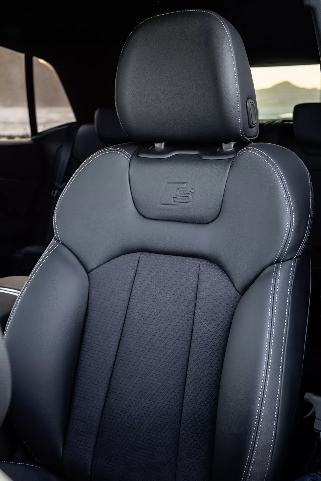 Vue intérieure de l'Audi Q8 (4M-Facelift) 2023 se concentrant sur le siège du conducteur avec des coutures détaillées, des matériaux de luxe et une ergonomie sportive, volant partiellement visible indiquant le côté conducteur