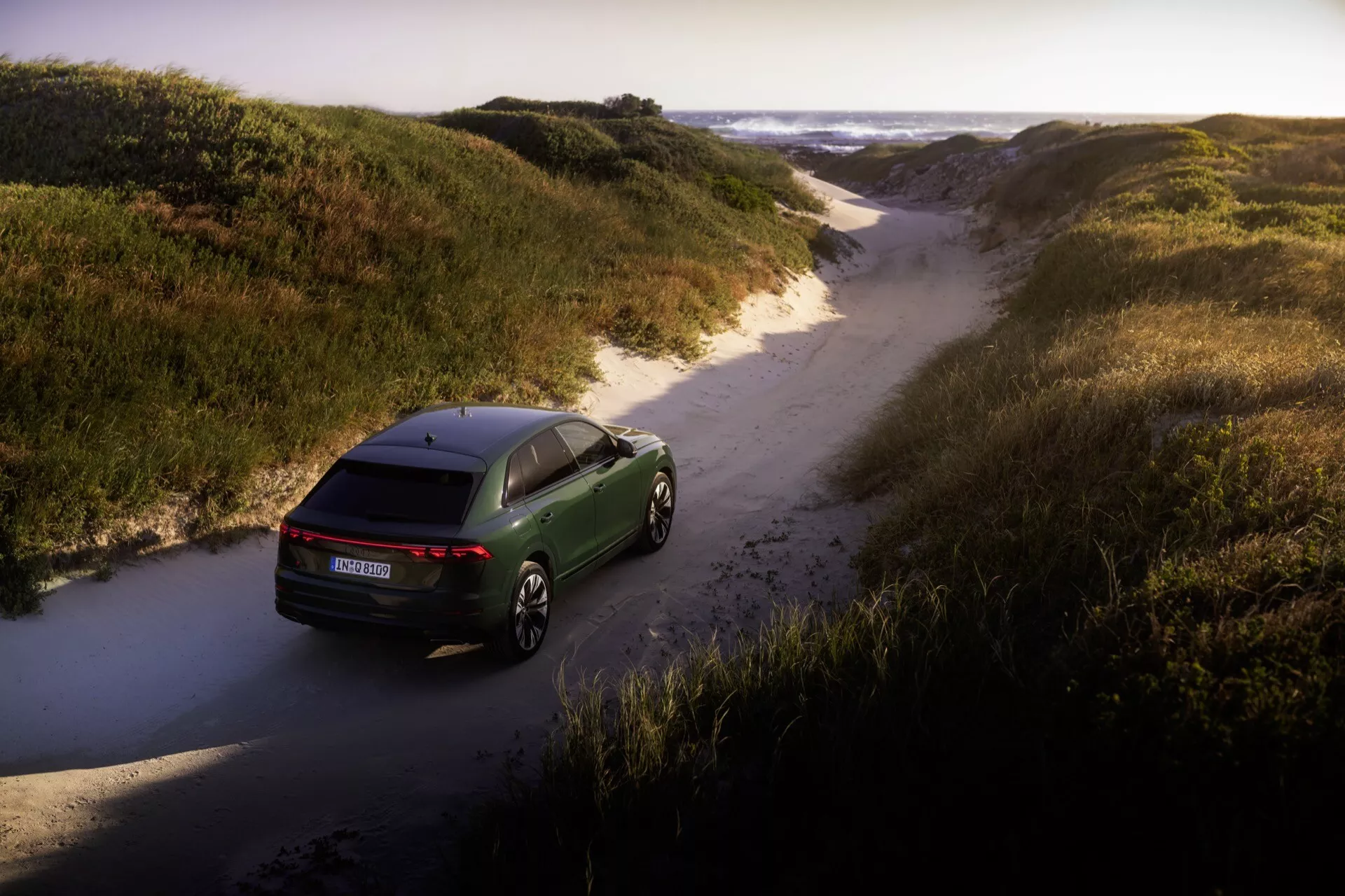 Audi Q8 2023 (4M-Facelift) capturée d'un point de vue aérien dévoilant son design aérodynamique, ses feux arrière LED et ses jantes en alliage haut de gamme dans un cadre naturel tout-terrain