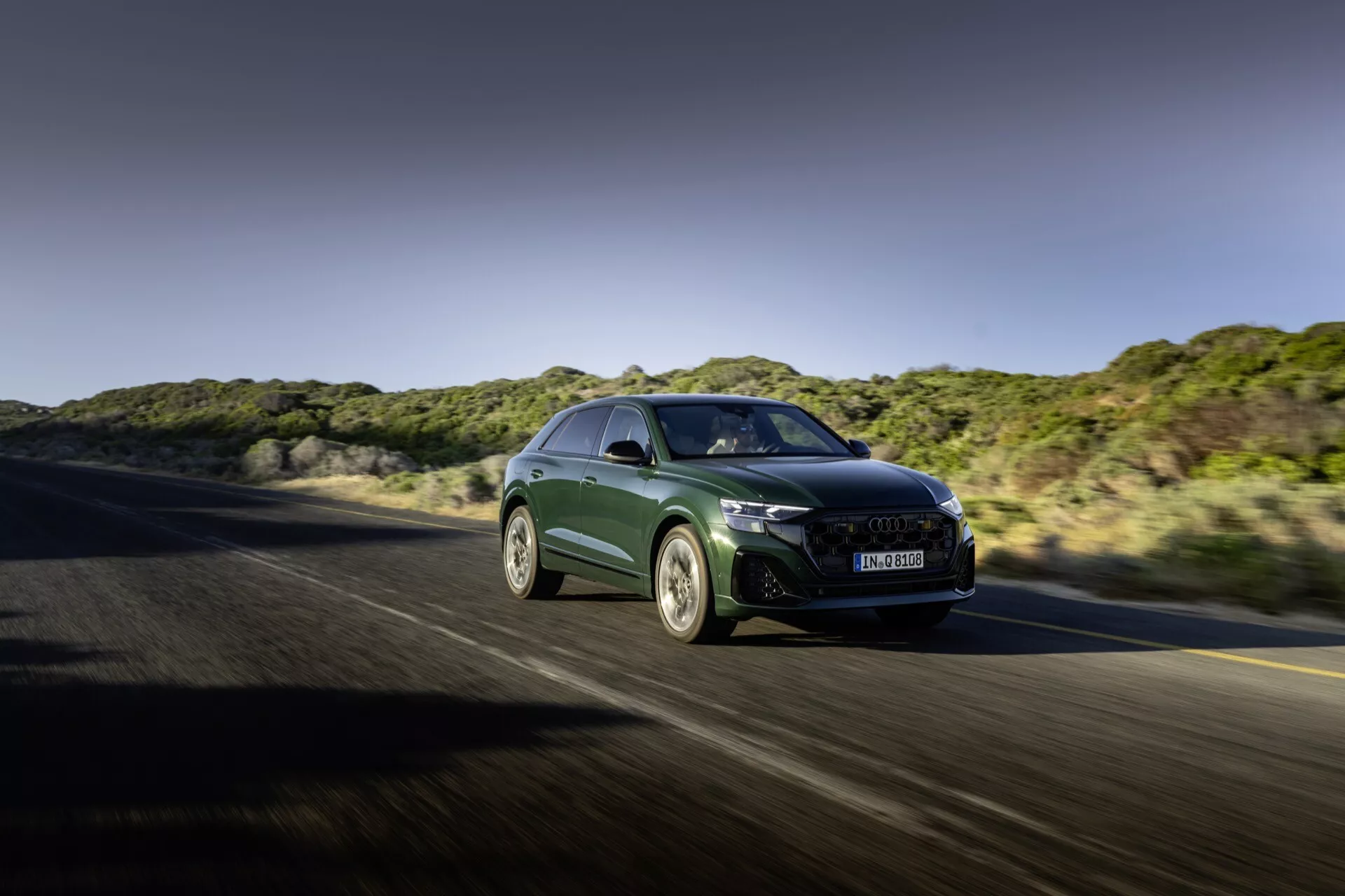 Audi Q8 2023 (4M-Facelift) en mouvement, présentant une forme aérodynamique, des phares LED aiguisés, une grande grille avec refroidissement avancé, des jantes alliage sportives et des fonctionnalités haute performance depuis un angle avant trois quartiers sur une autoroute