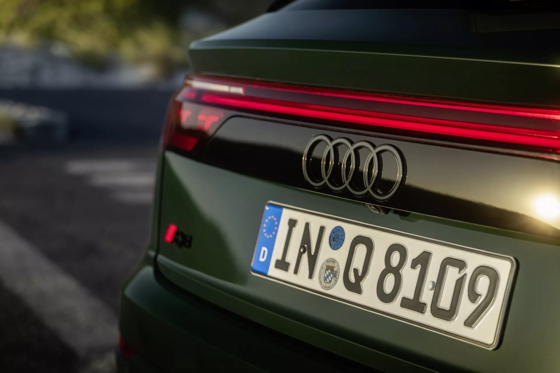 Vue arrière rapprochée d'une Audi Q8 verte de 2023 4M-Facelift présentant le badge Audi, bande LED horizontale, plaque d'immatriculation européenne d'Ingolstadt, becquet sportif, avec un design de hayon détaillé et une finition métallique polie.