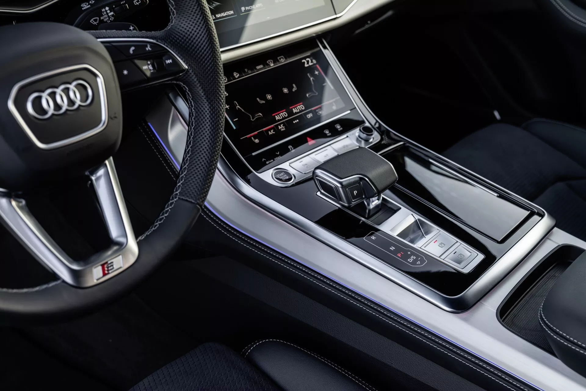 Vue aérienne de l'intérieur de l'Audi Q8 2023 centrée sur la console centrale avec le levier de vitesse et le panneau de contrôle multimédia, mettant en lumière les finitions luxueuses et les caractéristiques technologiques avancées