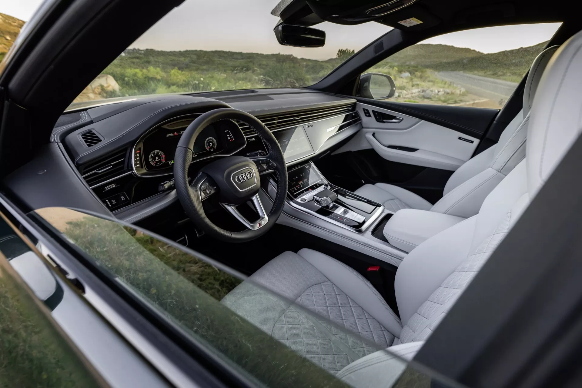 Vue de l'intérieur de l'Audi Q8 2023 (4M-Facelift) mettant en avant le poste de pilotage côté conducteur avec le cluster d'instruments numériques, le système d'infodivertissement tactile et les finitions de luxe telles que la garniture en cuir et les accents métalliques
