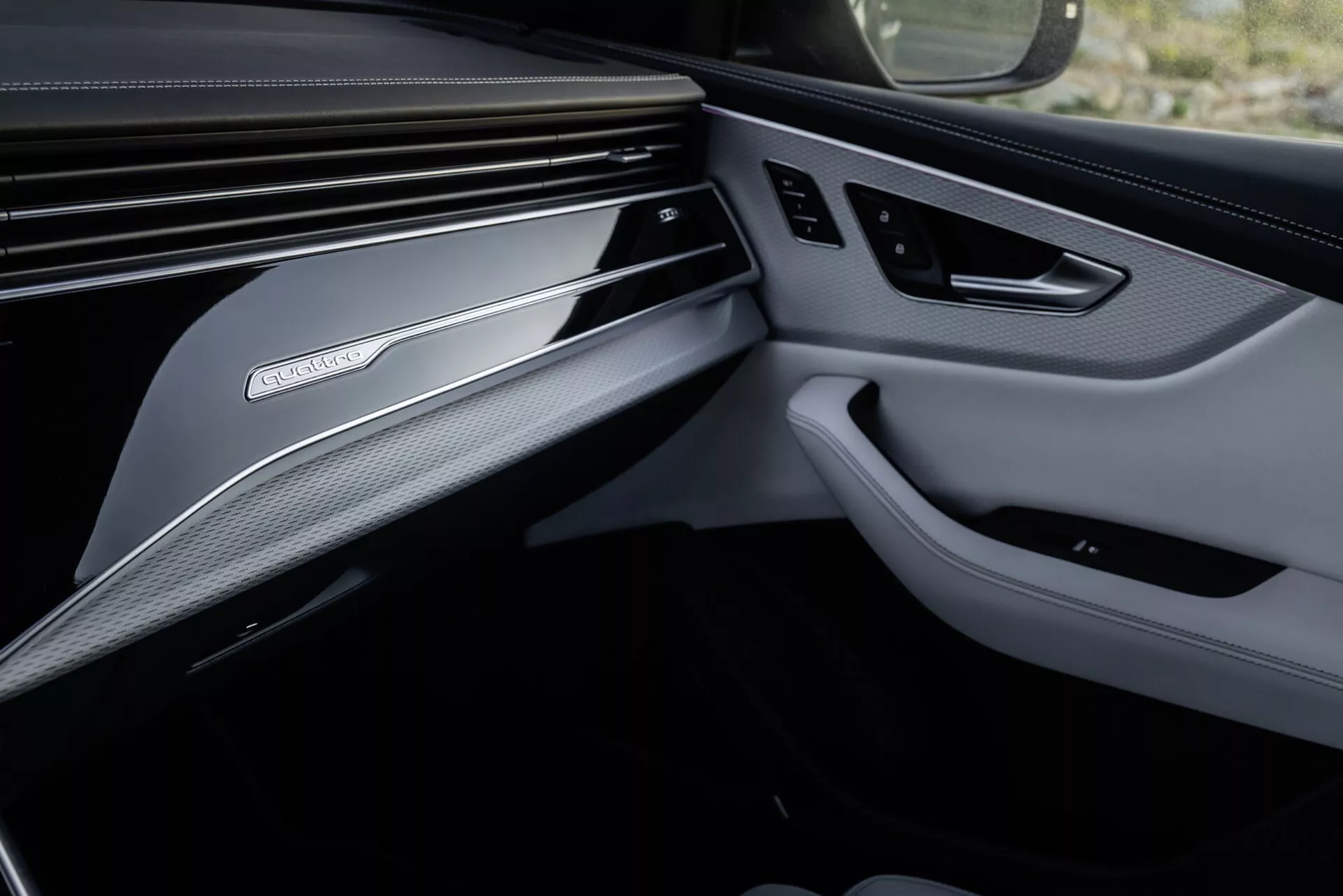 Photo intérieure de l'Audi Q8 2023 (4M-Facelift) mettant en avant le design de luxe du côté passager avant, montrant le tableau de bord et le panneau de porte avec des matériaux haut de gamme et des fonctionnalités technologiques