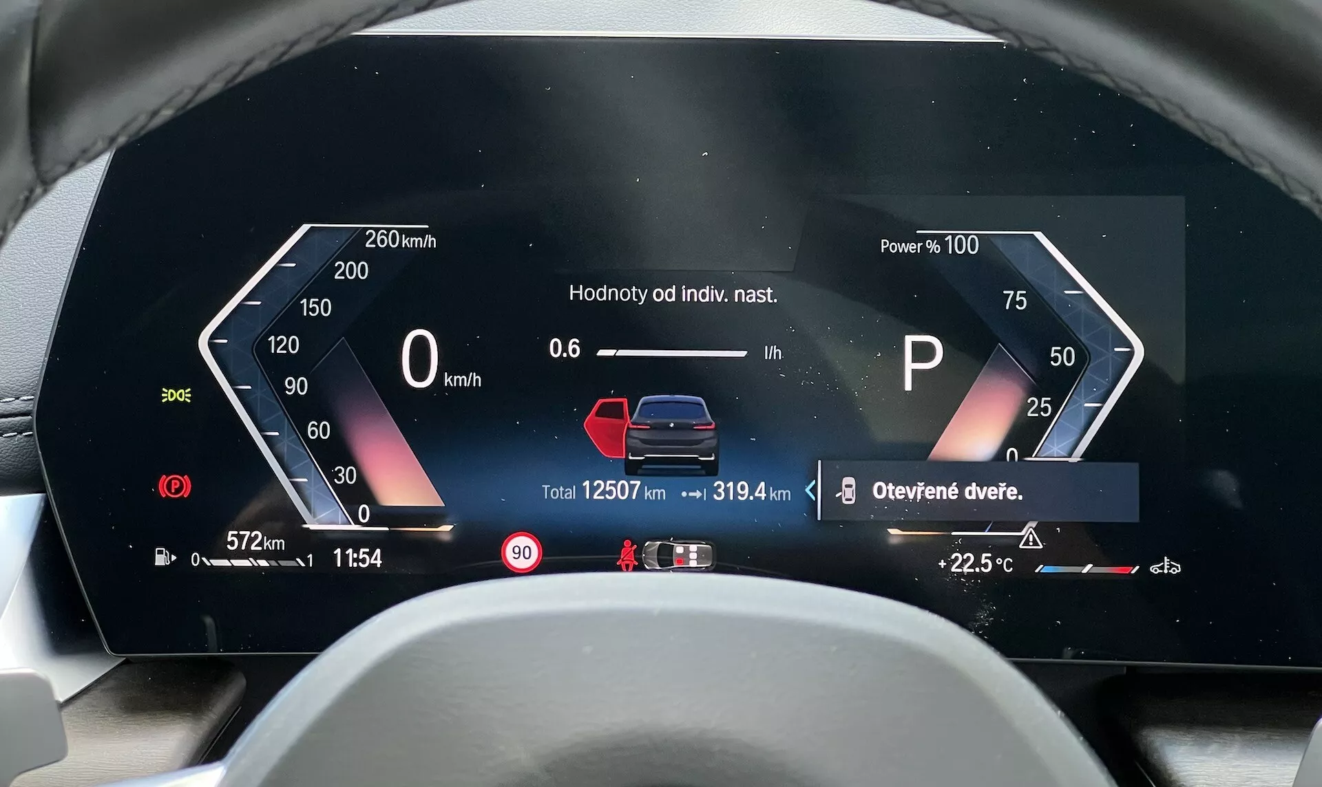 Tableau de bord numérique de la BMW Série 2 Active Gran Tourer 2022 affichant Compteur de vitesse, Utilisation de l'énergie, Indicateur de sélection de vitesse, Graphique d'état du véhicule, Compteur partiel, Odomètre, Température externe, Notifications d'avertissement, Heure, Température interne et Jauge de carburant depuis la perspective du conducteur en tchèque ou slovaque