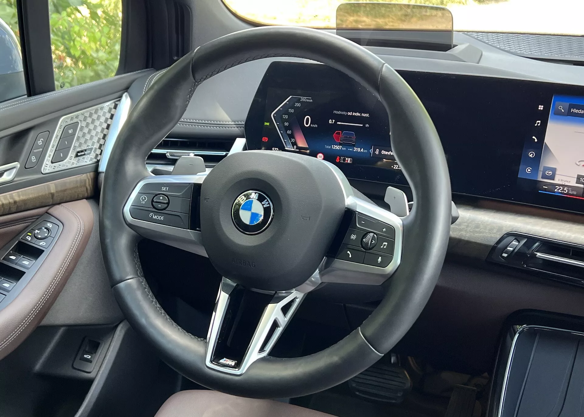 Vue intérieure depuis le siège du conducteur d'une BMW Série 2 Active Gran Tourer 2022, centrée sur le volant avec boutons multifonctions et le tableau de bord numérique haute définition, encadré par des matériaux haut de gamme et une partie de l'écran d'infodivertissement