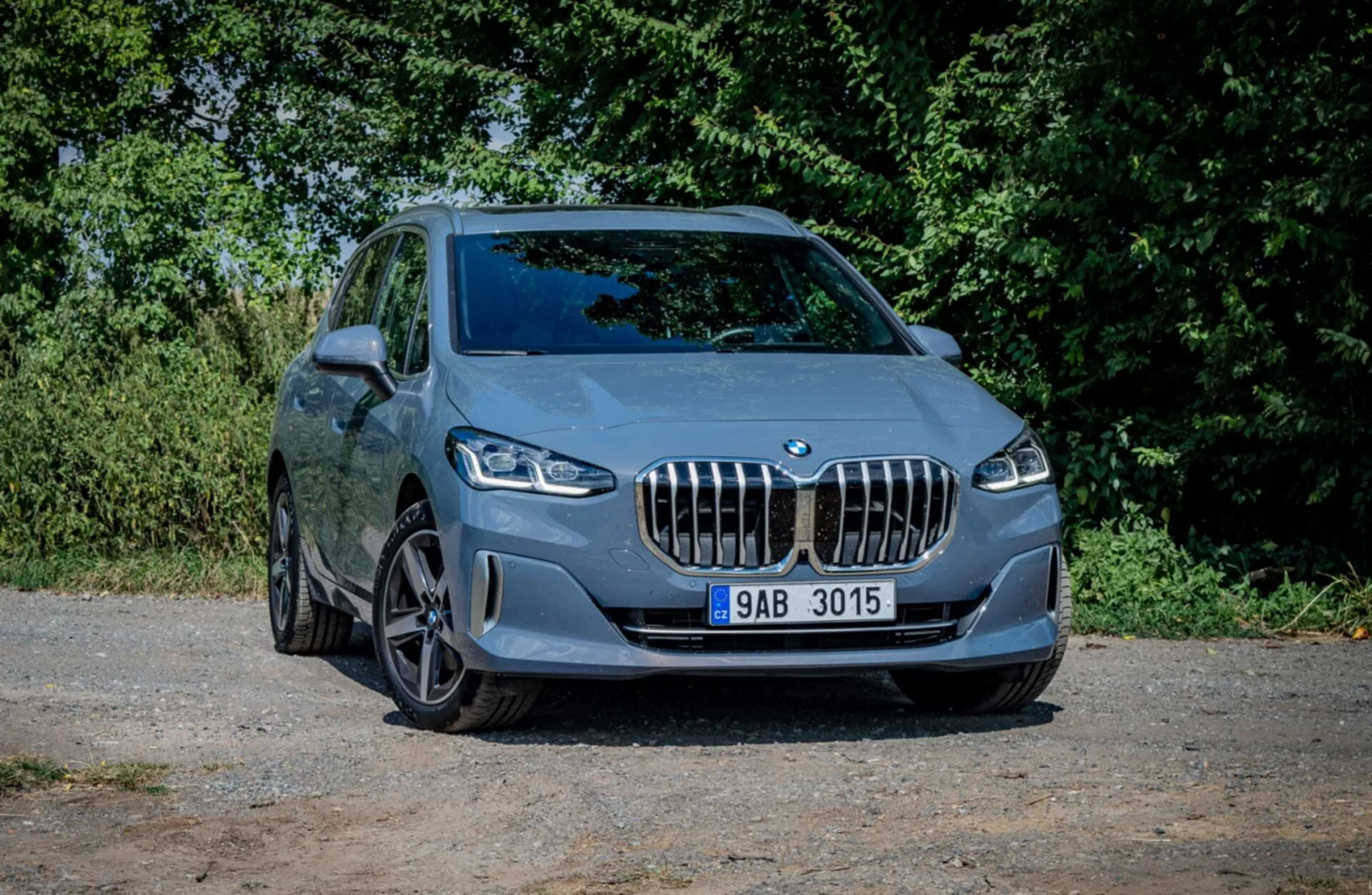 BMW Série 2 Active Tourer de 2022 stationnée sur du gravier présentant son design sportif et ses caractéristiques modernes sous un angle avant de trois quarts avec un arrière-plan naturel