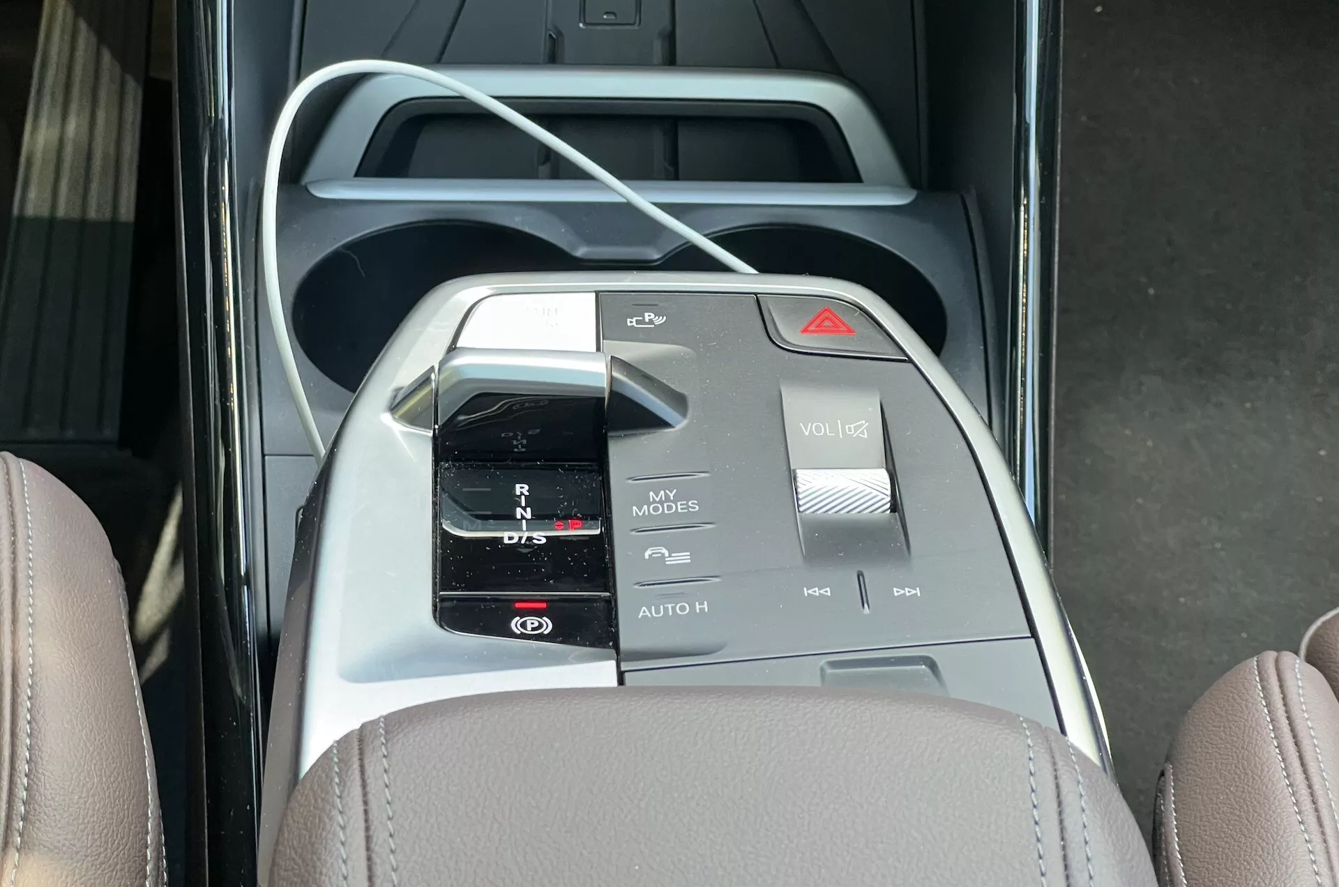 Vue aérienne de la console centrale de BMW Série 2 Active Tourer 2022 avec sélecteur de vitesse automatique, porte-gobelets, interface de commande multimédia avec divers boutons et interrupteurs, et design intérieur bicolore avec accents en cuir et métalliques