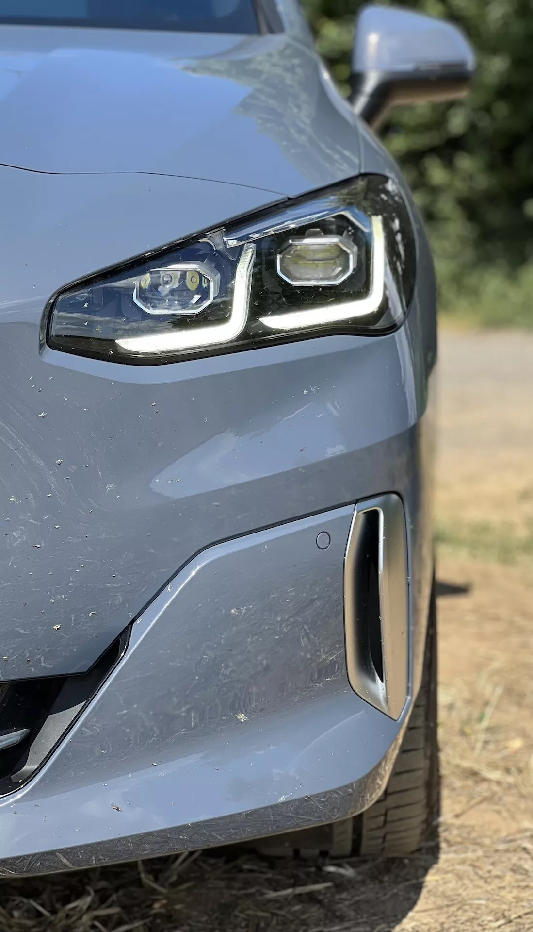 Vue en gros plan du côté avant gauche de la BMW Série 2 Active Gran Tourer 2022 avec phare LED et pare-chocs aérodynamique doté d'un capteur de stationnement, démontrant la technologie avancée et le design.