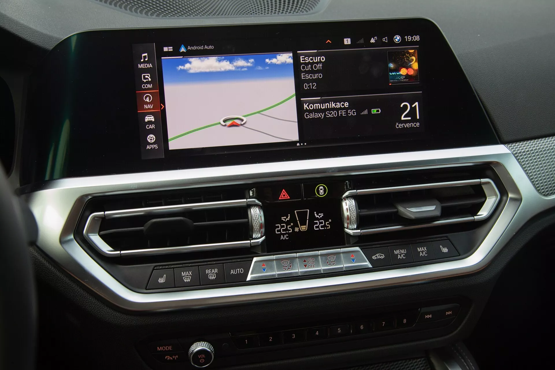 La console centrale de la BMW Série 2 Coupé 2022 est mise en avant, montrant le système d'infotainment moderne et les commandes de climatisation de cette voiture. L'image capture un grand écran tactile couleur affichant une carte de navigation, des icônes d'intégration Bluetooth ou smartphone et une horloge. Sous l'écran se trouvent deux aérateurs centraux avec des persiennes réglables et un panneau élégant avec des boutons tactiles et un écran LCD pour le contrôle de la climatisation bi-zone. Le design intérieur, avec des accents métalliques brossés et des textures semblables à la fibre de carbone, reflète un environnement luxueux et axé sur la technologie.
