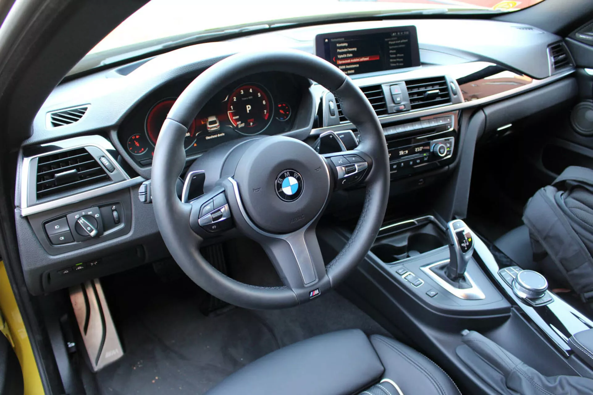 Vue intérieure d'une coupé BMW Série 4 de 2013 du point de vue du conducteur montrant le volant, le tableau de bord, la console centrale avec commandes multimédia et climatiques, le levier de vitesses et les finitions de luxe