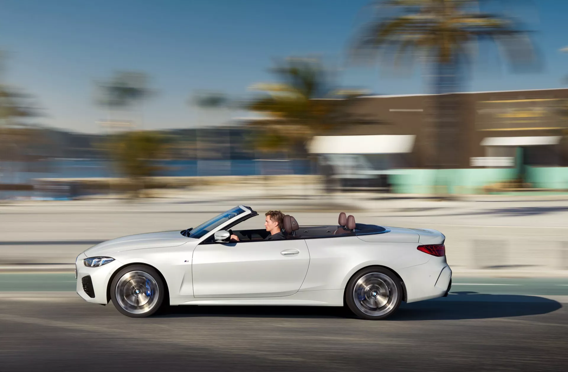 Profil latéral dynamique de la BMW Série 4 Cabriolet 2024 (G22-G23-G26-G82-G83 restylage) en mouvement avec design des roues visible et détails intérieurs de luxe, démontrant vitesse et technologie avancée des phares LED.