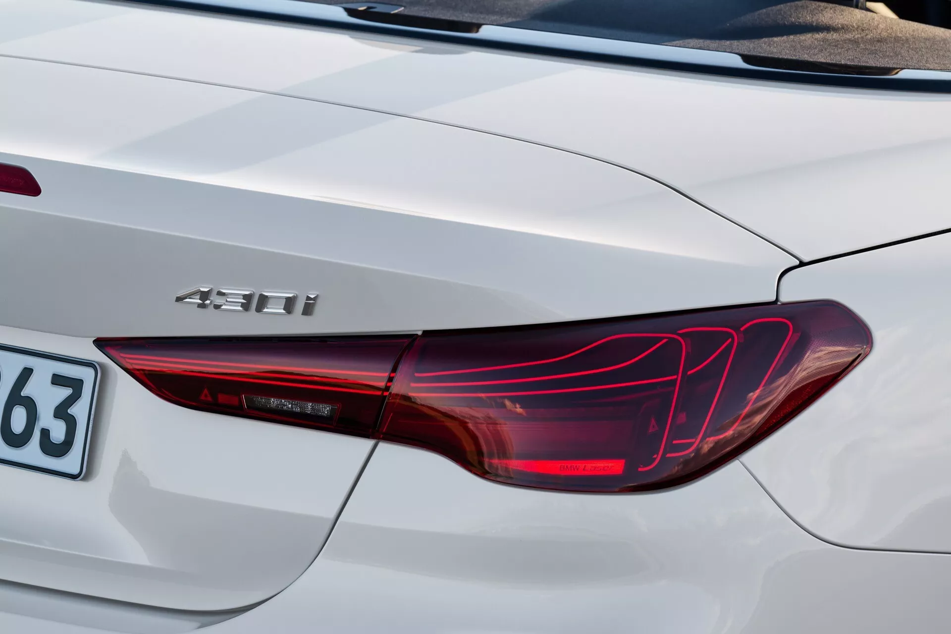 Gros plan sur le coin arrière de la BMW Série 4 2024 (G22-G23-G26-G82-G83-Facelift) montrant le design de feu arrière LED, l'insigne hybride '450h' et une partie du couvercle de coffre en finition argent-blanc