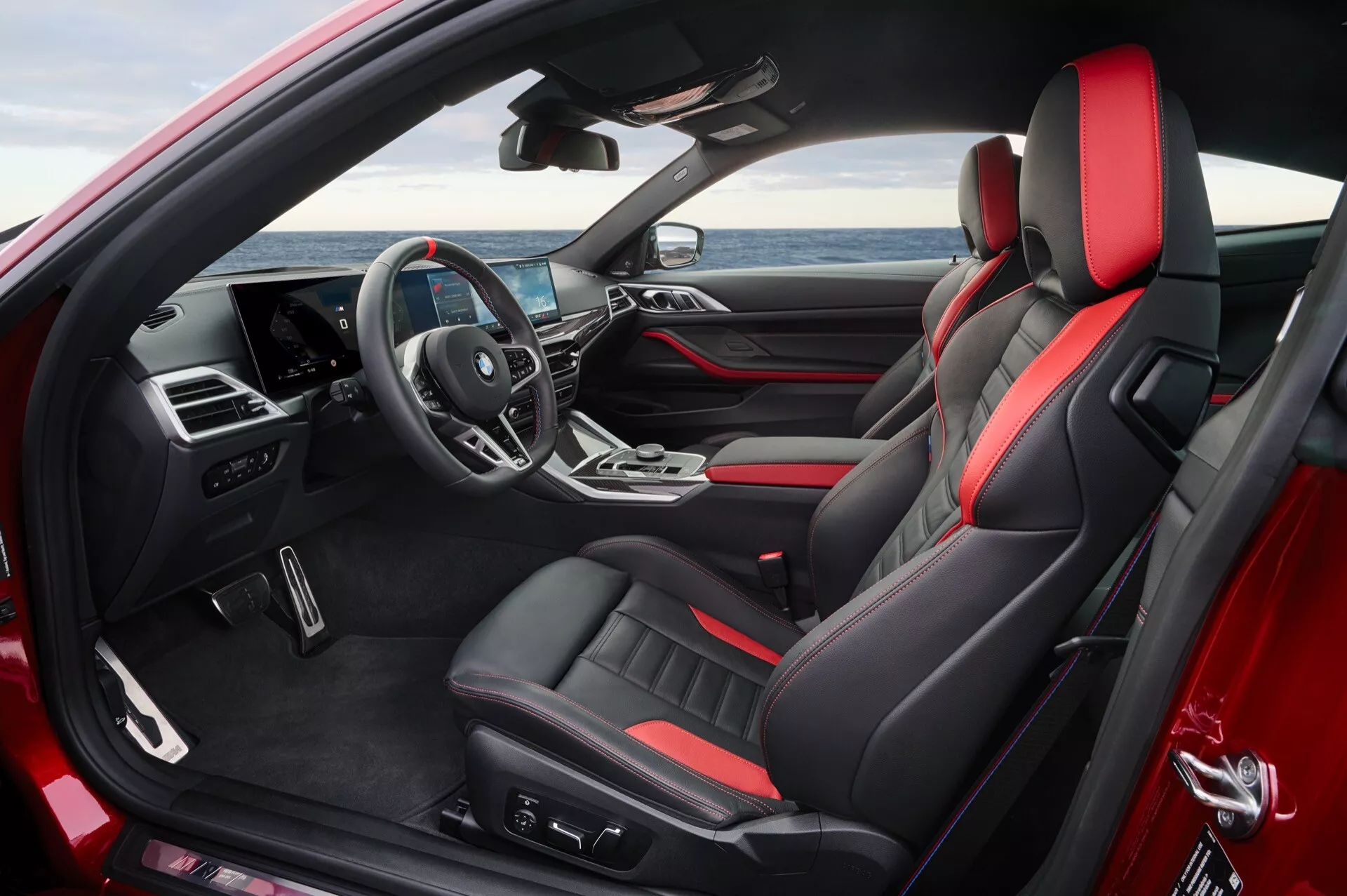 Vue intérieure de la BMW Série 4 2024 (G22-G23-G26-G82-G83 restylée) présentant des sièges sportifs en cuir noir avec passepoil rouge, console centrale avancée et cockpit du conducteur à la pointe de la technologie
