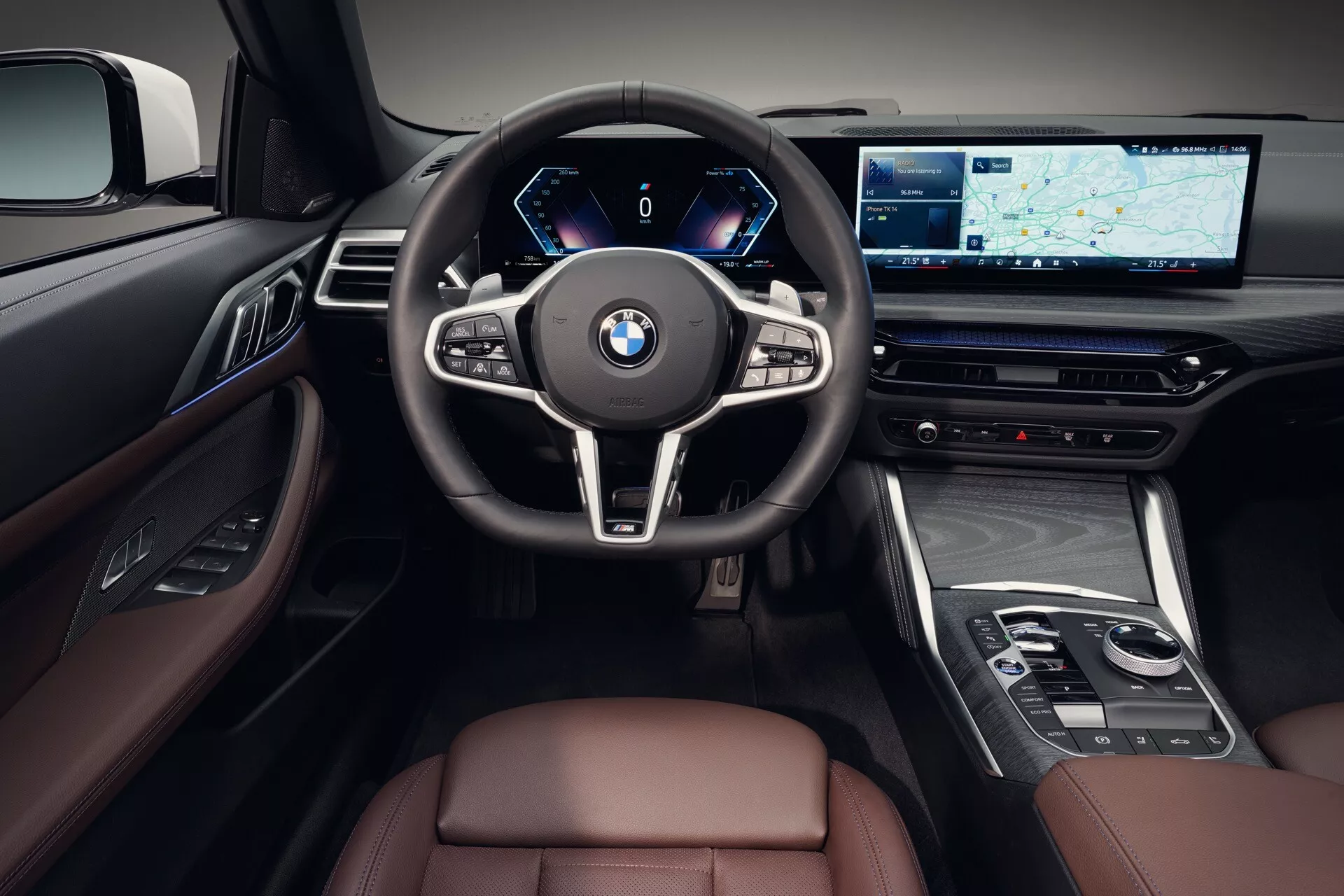 Intérieur de la BMW Série 4 2024 (G22-G23-G26-G82-G83 Facelift), centré sur la zone du conducteur avec tableau de bord numérique, volant multifonction, grand écran d’infodivertissement avec navigation, finitions de luxe avec cuir et bois, depuis une perspective à la première personne