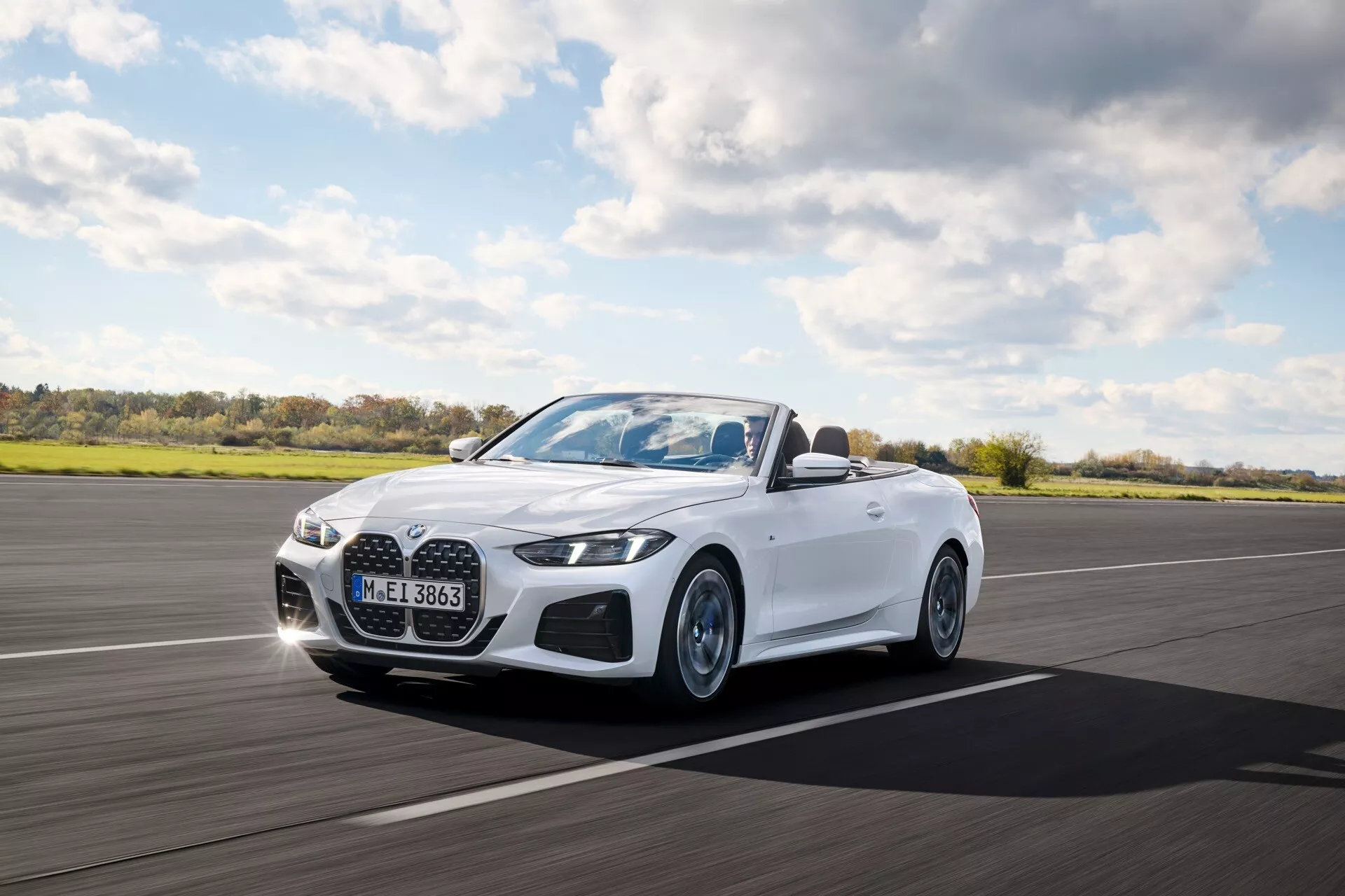 BMW Série 4 Cabriolet 2024 (G22-G23-G26-G82-G83 Facelift) en mouvement, présentant des phares LED, une grille avant proéminente et une extérieur blanc depuis une vue trois quarts avant