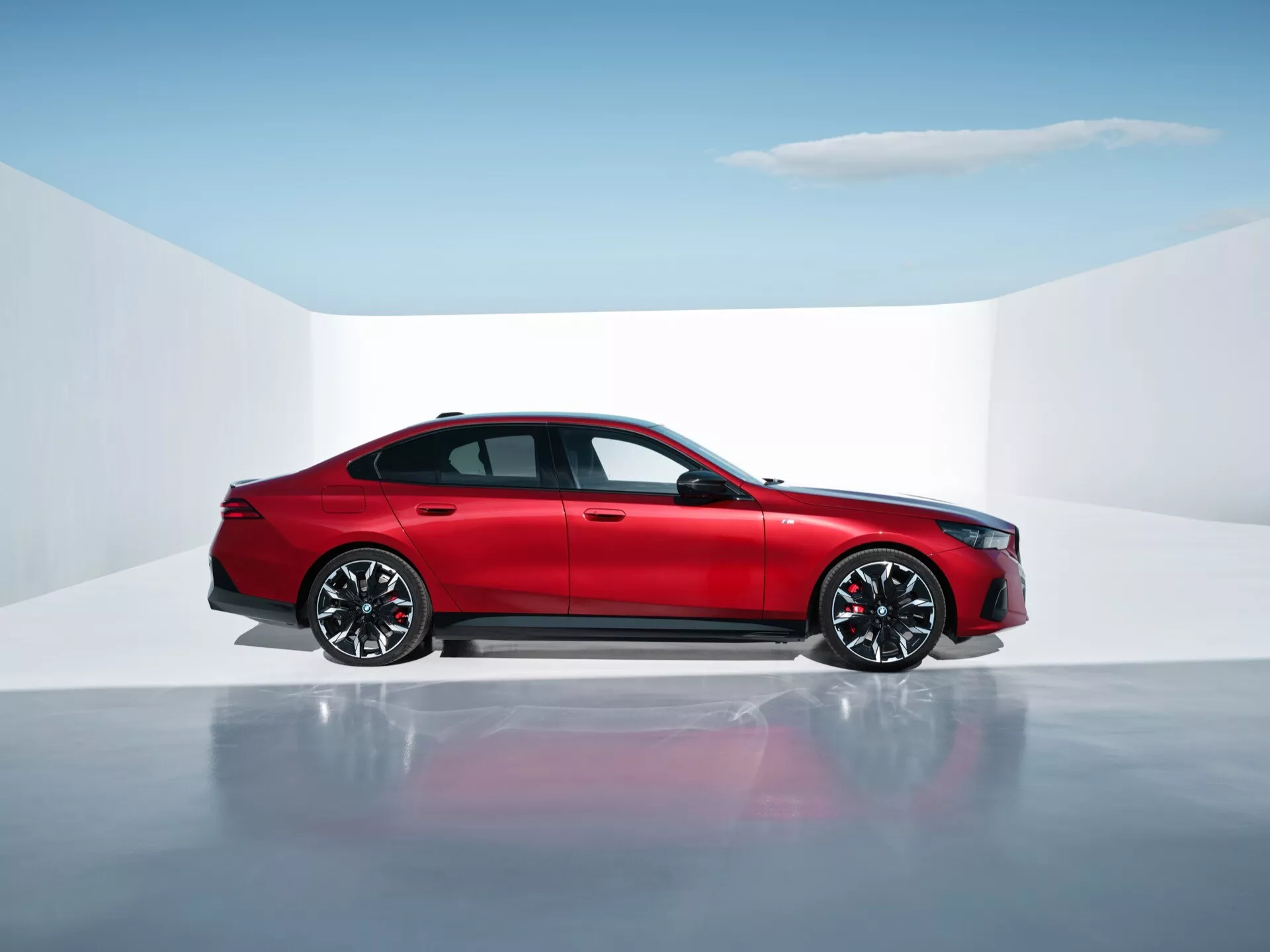 Berline rouge à quatre portes BMW Série 5 (G60-G61) en studio avec sol réfléchissant, montrant profil latéral, design moderne et caractéristiques avancées