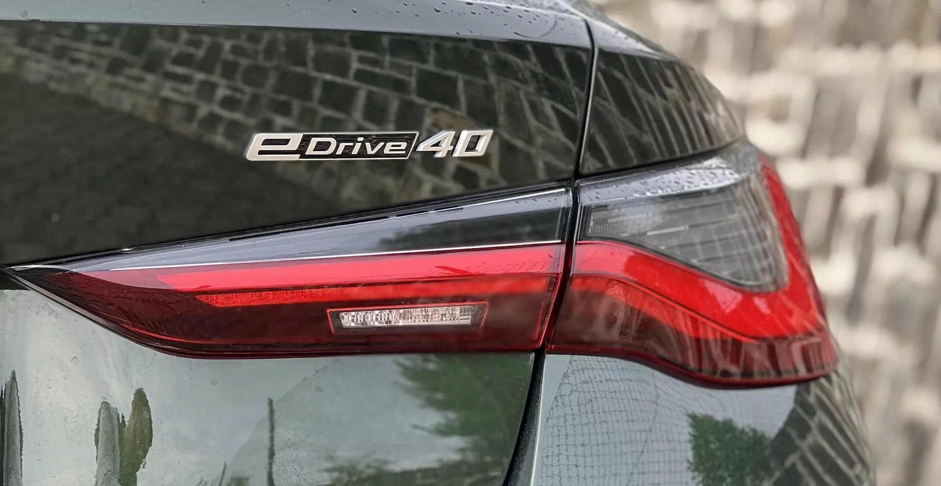 Vue rapprochée du coin arrière d'une BMW i4 2021 mettant en évidence le feu arrière et le badge eDrive 40 avec technologie LED et peinture réfléchissante.