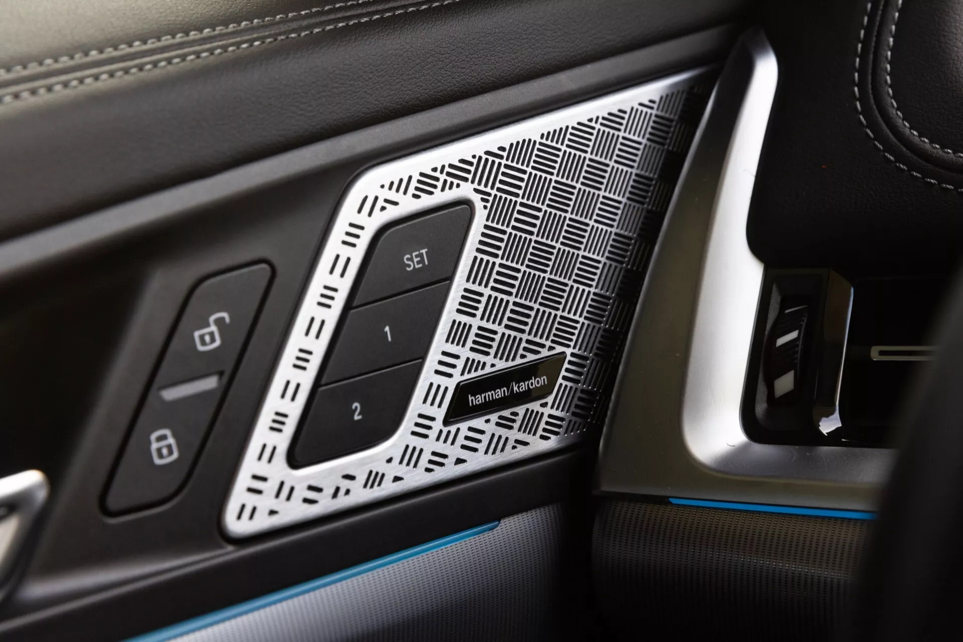 Vue rapprochée du panneau de porte côté conducteur dans une BMW X1 2022 (U11), mettant en vedette des détails de finition de luxe tels que le cuir avec couture contrastante, insert géométrique, boutons de mémoire de siège et éclairage d'ambiance