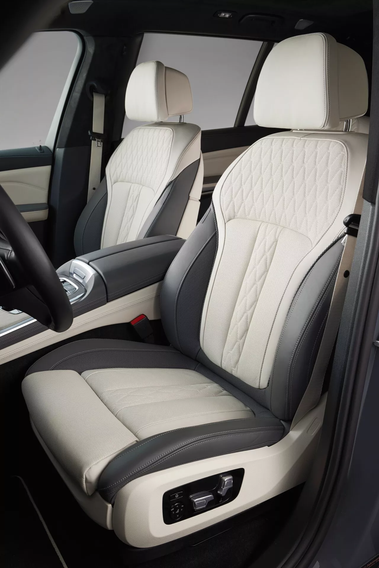 Vue détaillée de l'intérieur de la BMW X7 2022 (G07-facelift), se concentrant sur le siège passager en cuir bicolore haut de gamme avec coutures en losange, réglages électroniques, assorti à une conception luxueuse de la porte et de la console centrale