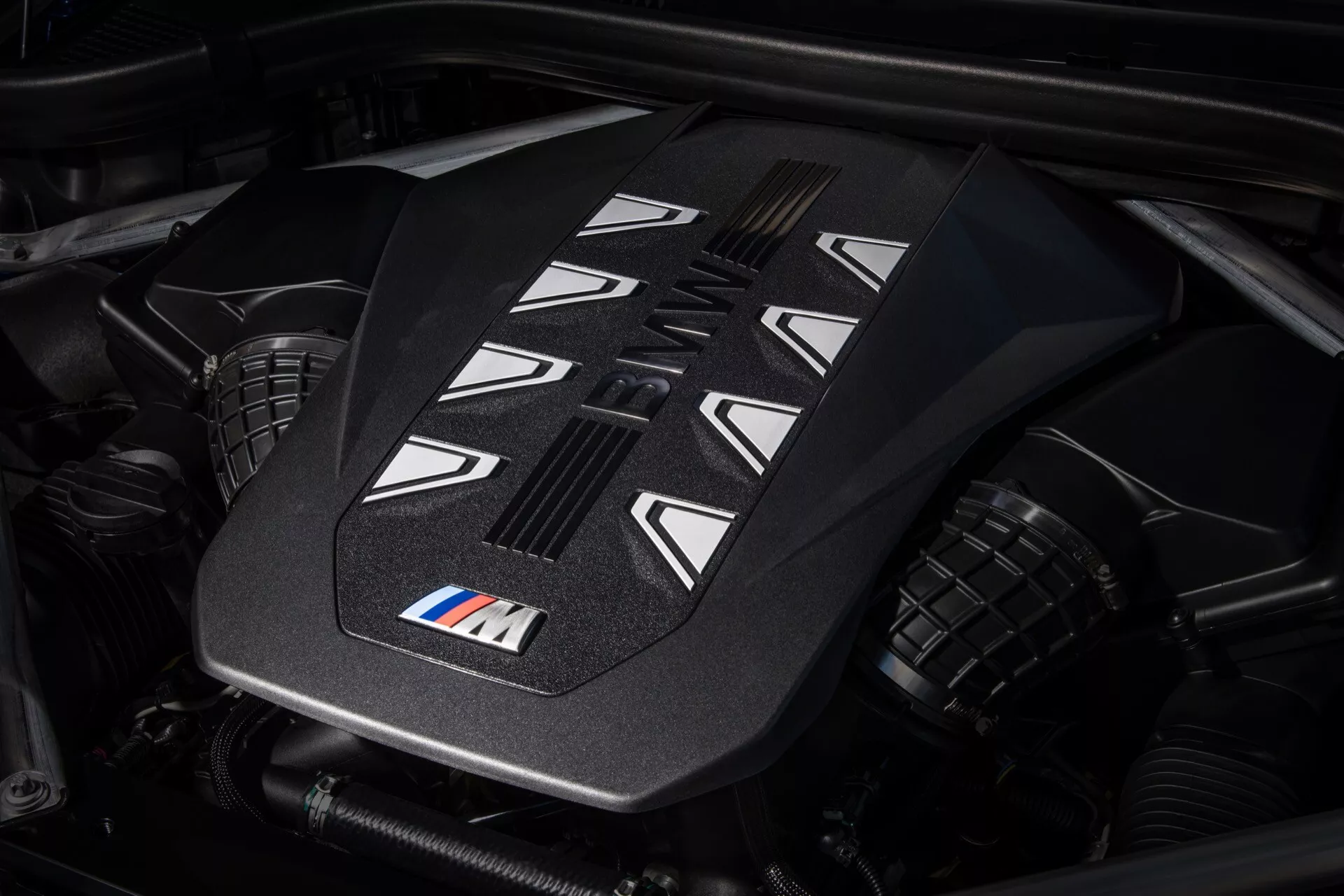Vue rapprochée du couvercle du moteur haute performance dans la BMW X7 2022 (G07-Facelift) avec badge M, présentant des caractéristiques de conception avancées et des fentes de refroidissement