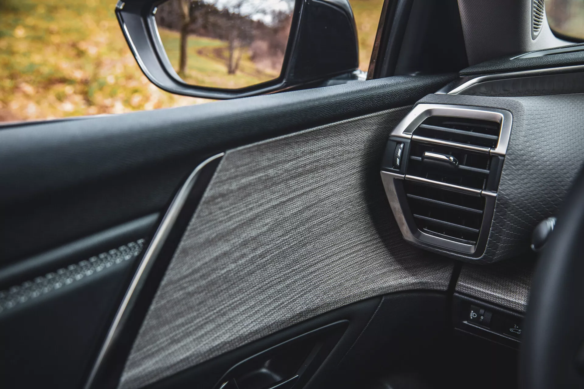 Vue détaillée de la porte côté passager du Citroen C5-X 2022, exposant un design de luxe avec du cuir texturé, des garnitures brillantes et une grille d'aération de contrôle climatique