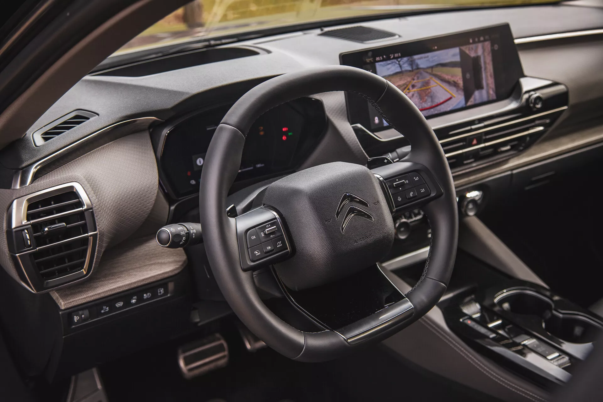 Vue rapprochée de l’intérieur du Citroën C5-X 2022 montrant le volant avec des boutons multifonctions, un tableau de bord numérique du point de vue du passager et un système d'infodivertissement tactile